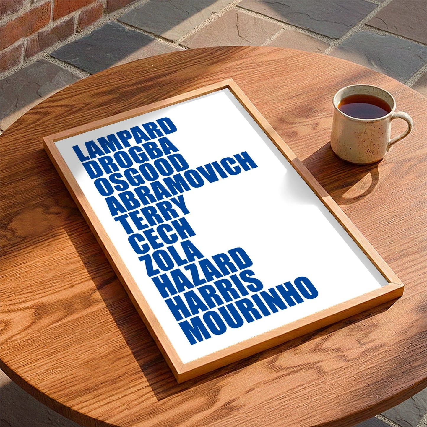 Framed print laying on a table beside a mug of tea