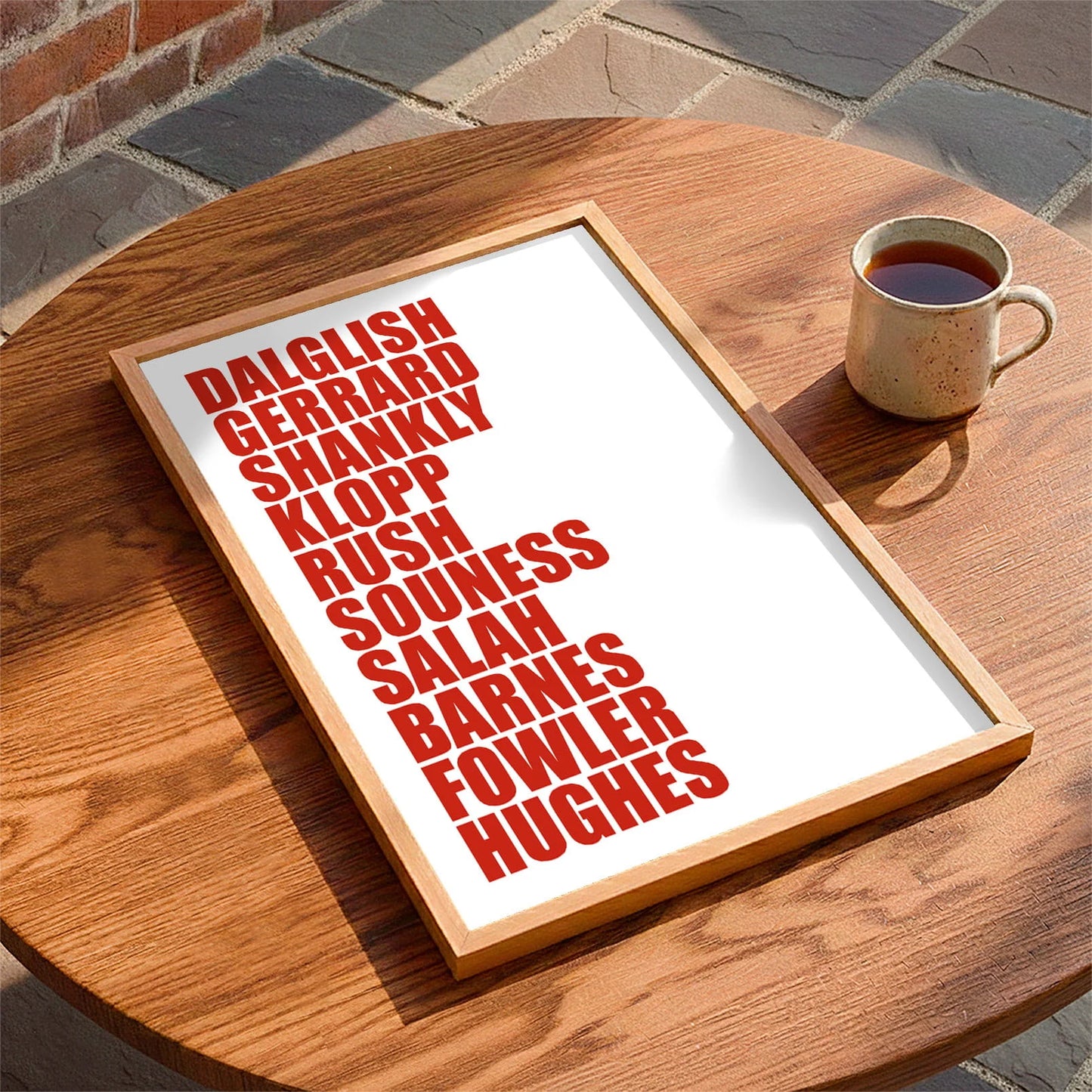 Framed print laying on a table beside a mug of tea