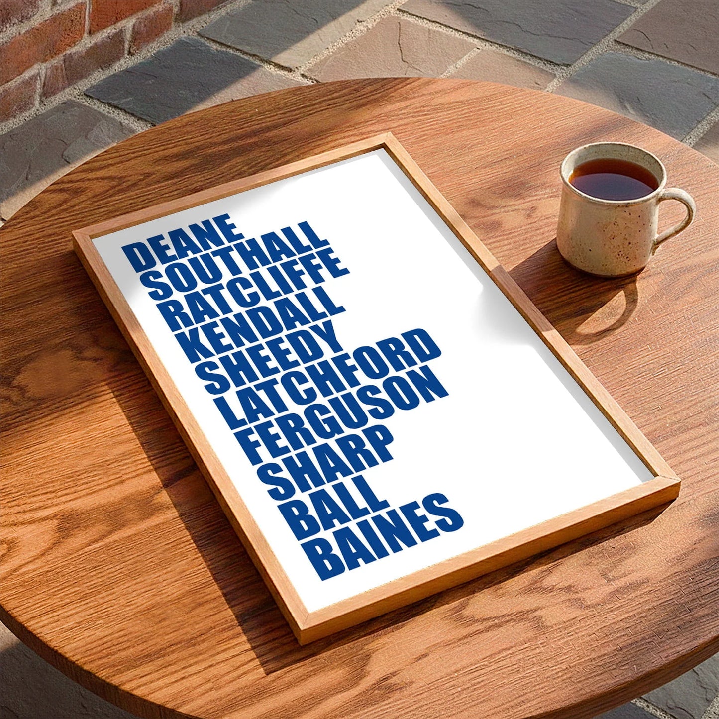 Framed print laying on a table beside a mug of tea