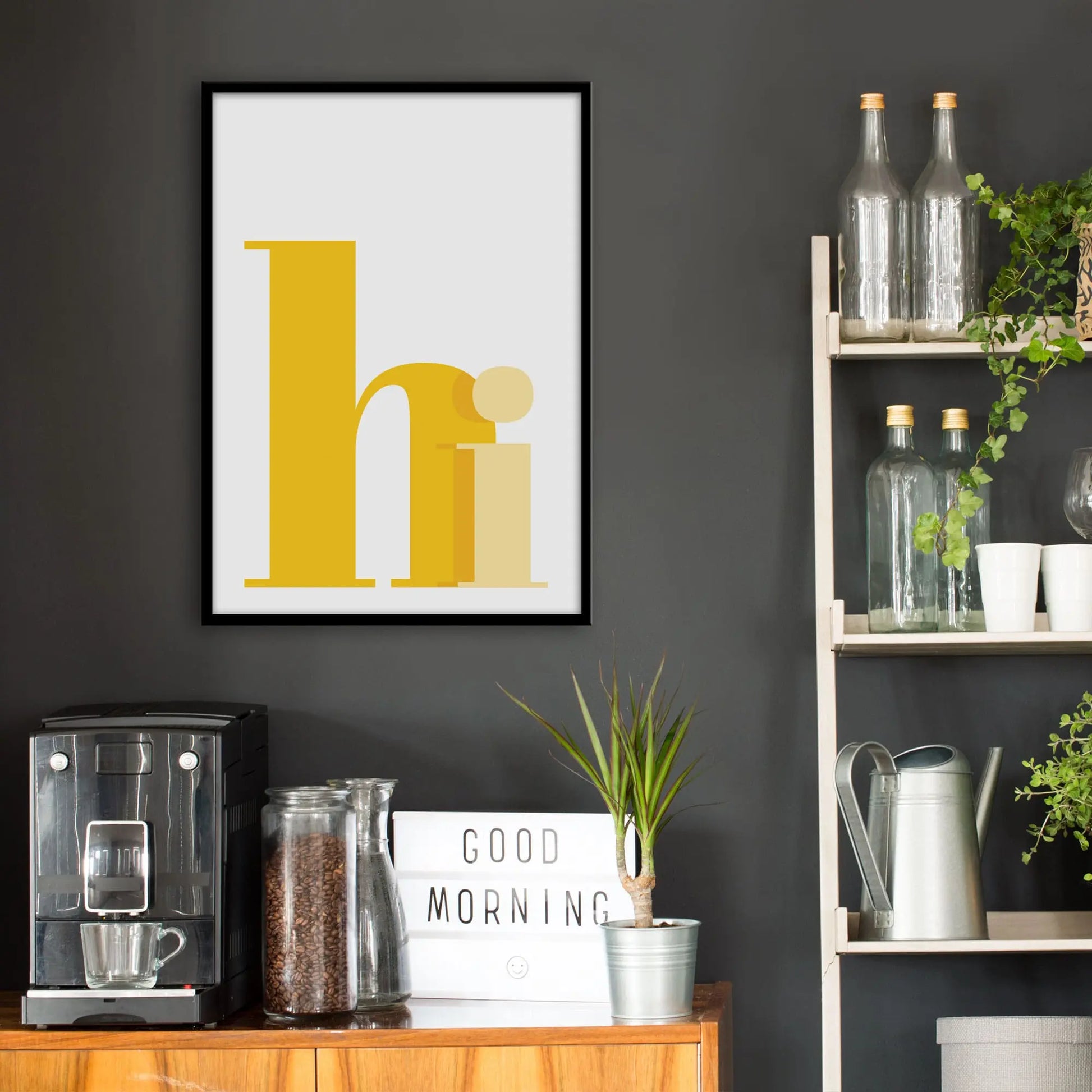 Kitchen wall infront of which is a sideboard with a coffee machine and a set of shelves holding bottles and plants. On the wall above the sideboard is the framed print in a black frame on a dark grey wall.