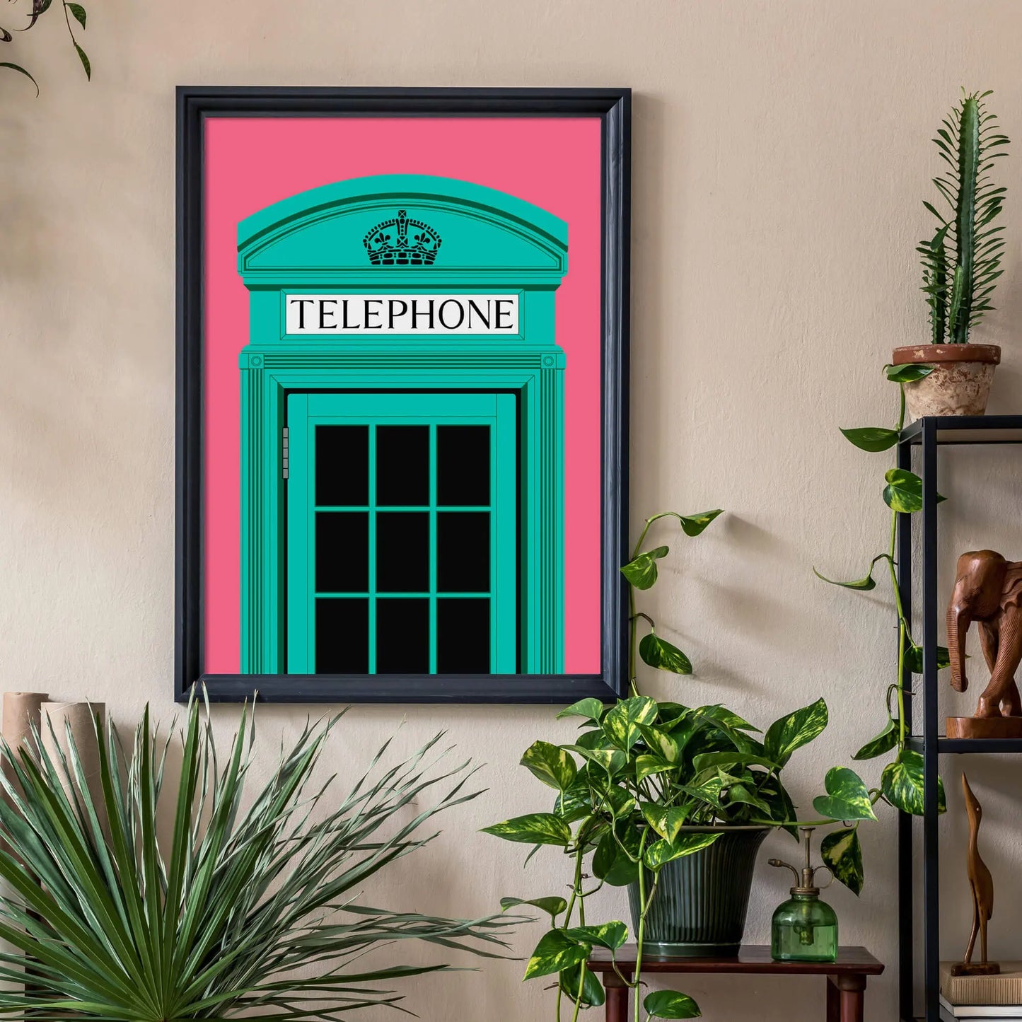 Black framed print on cream wall surrounded by various indoor plants on shelves and the floor.