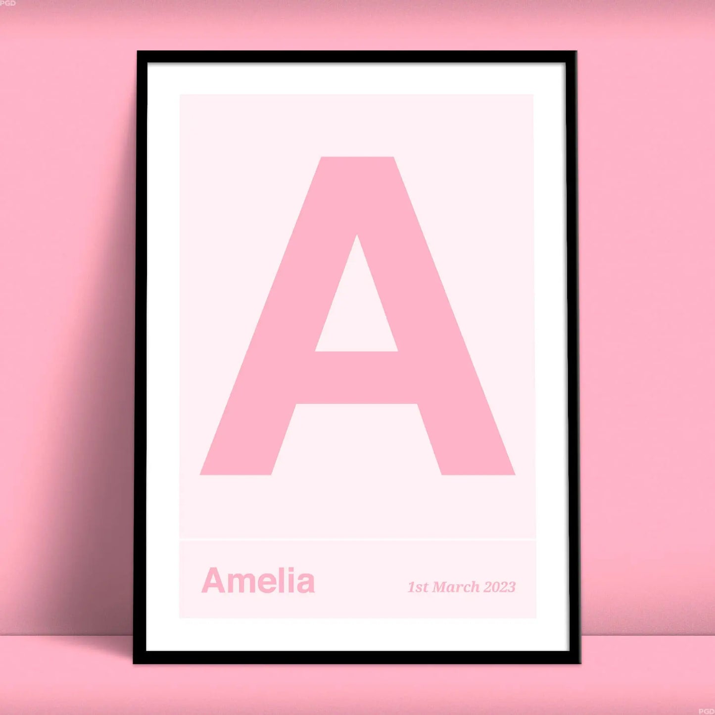 Large name initial print. Pink letter on a light pink background under which is a name and date from Purest Green Prints