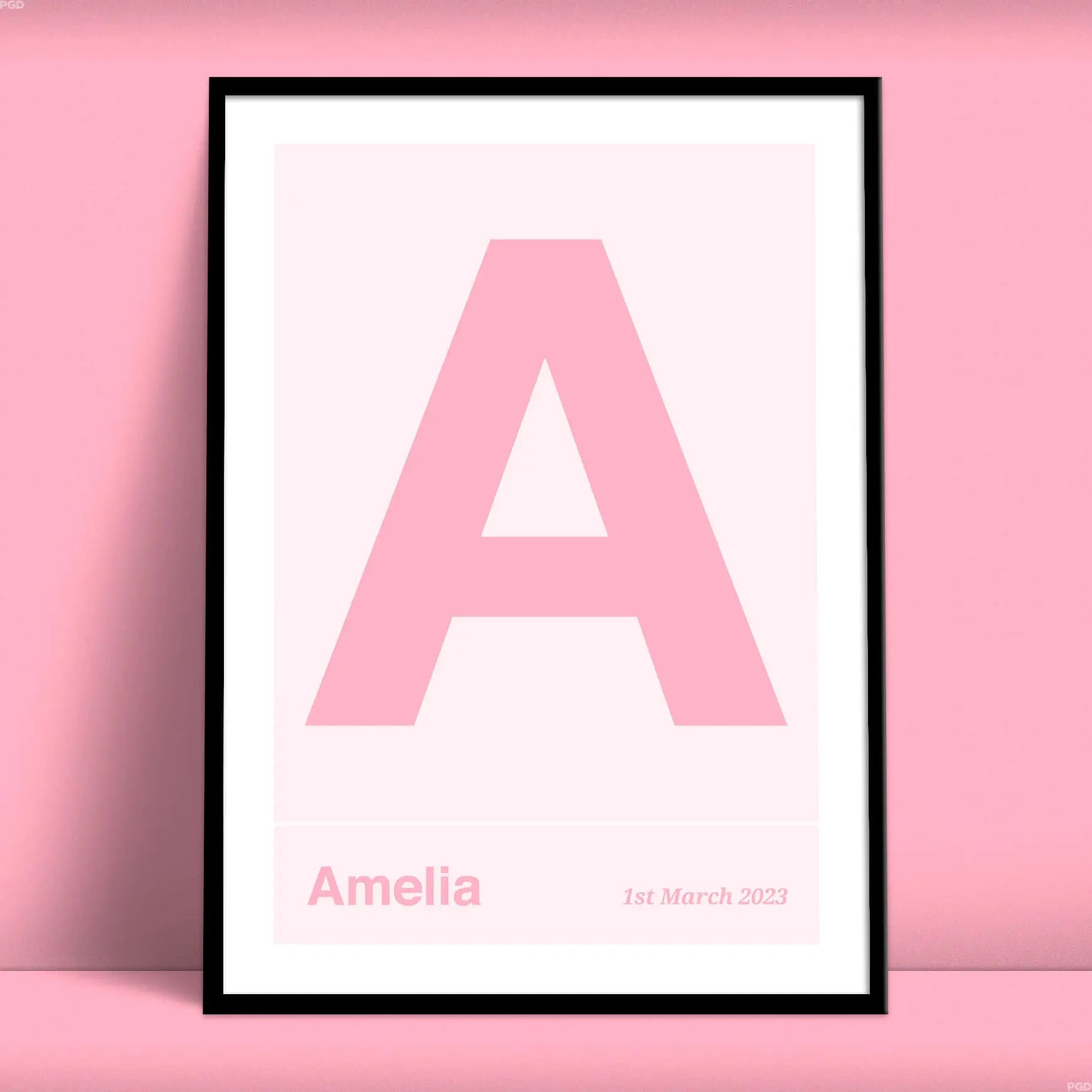 Large name initial print. Pink letter on a light pink background under which is a name and date from Purest Green Prints