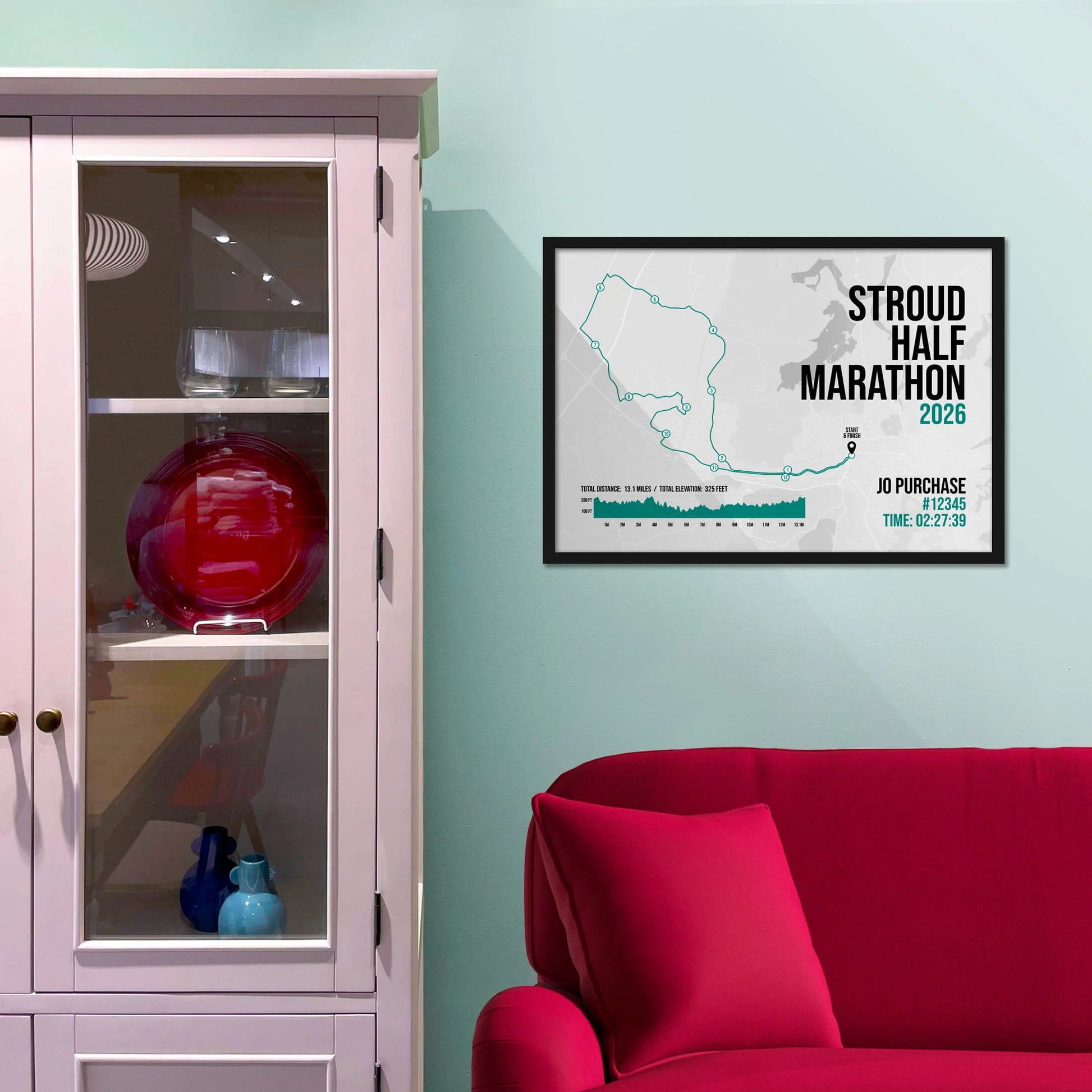 Framed picture on a baby blue wall beside pink shelving