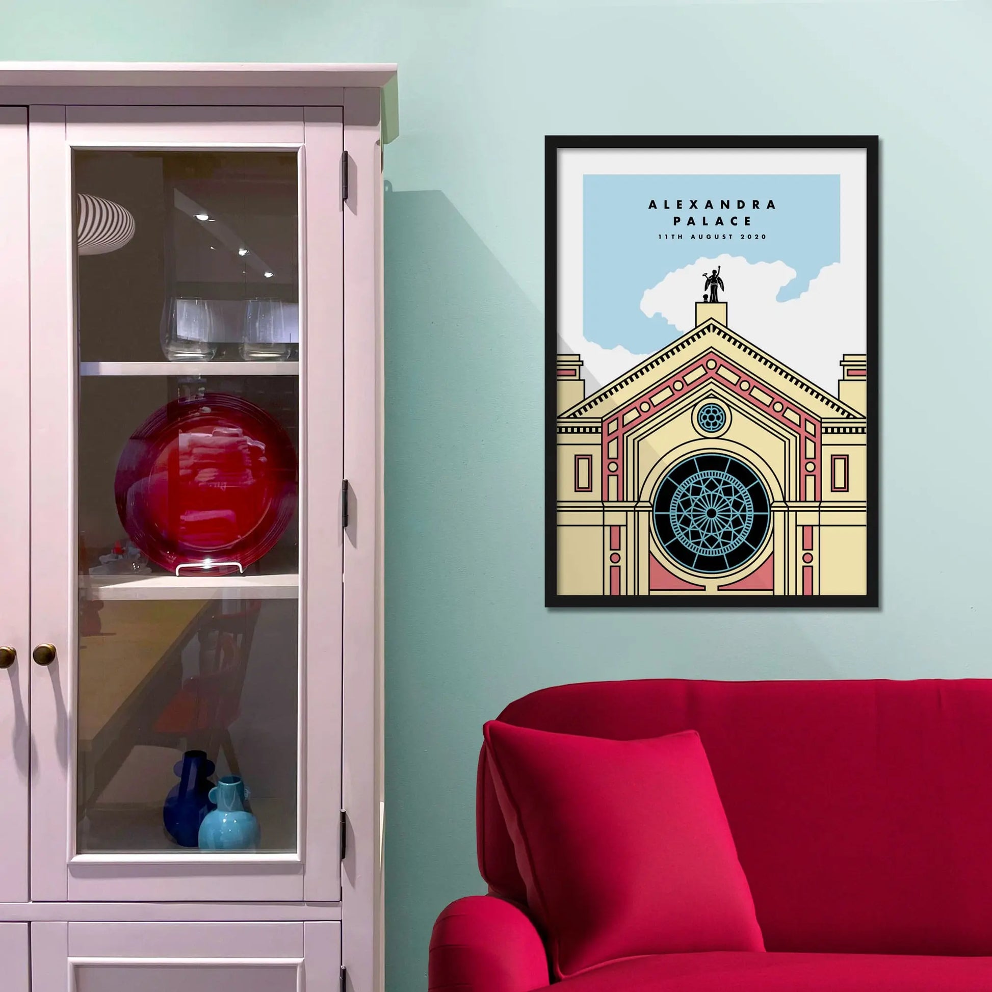Framed picture on a baby blue wall beside pink shelving