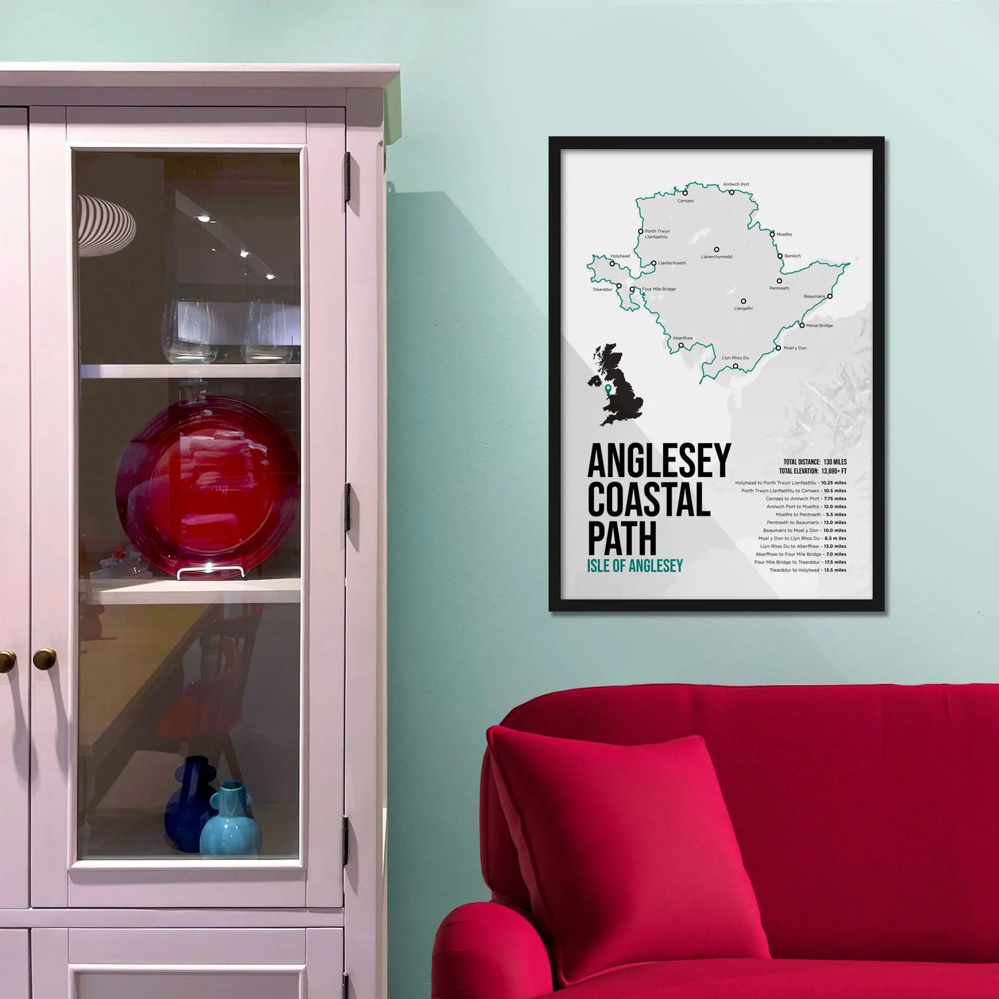 Framed map of Anglesey Coastal Path on a wall above a red sofa.