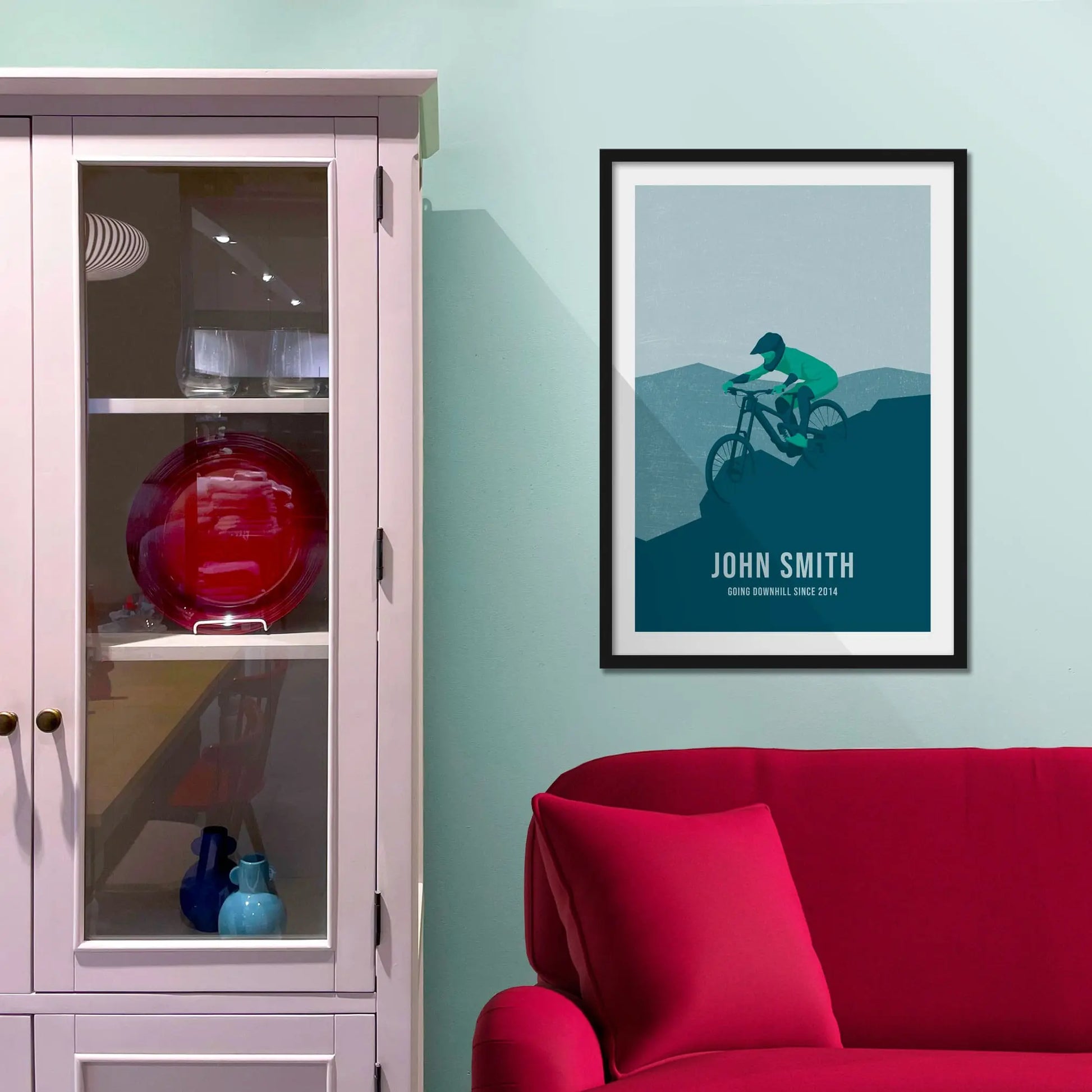Framed picture on a baby blue wall beside pink shelving