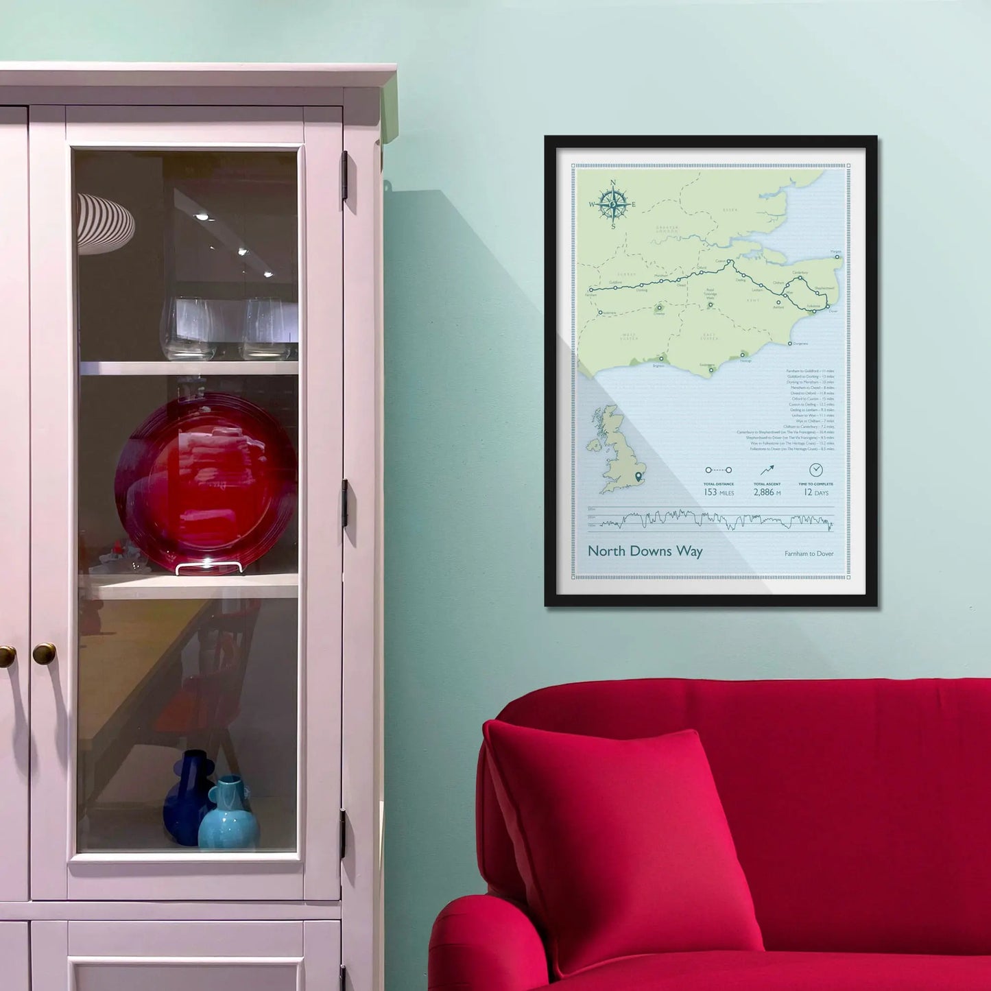 Framed picture on a baby blue wall beside pink shelving