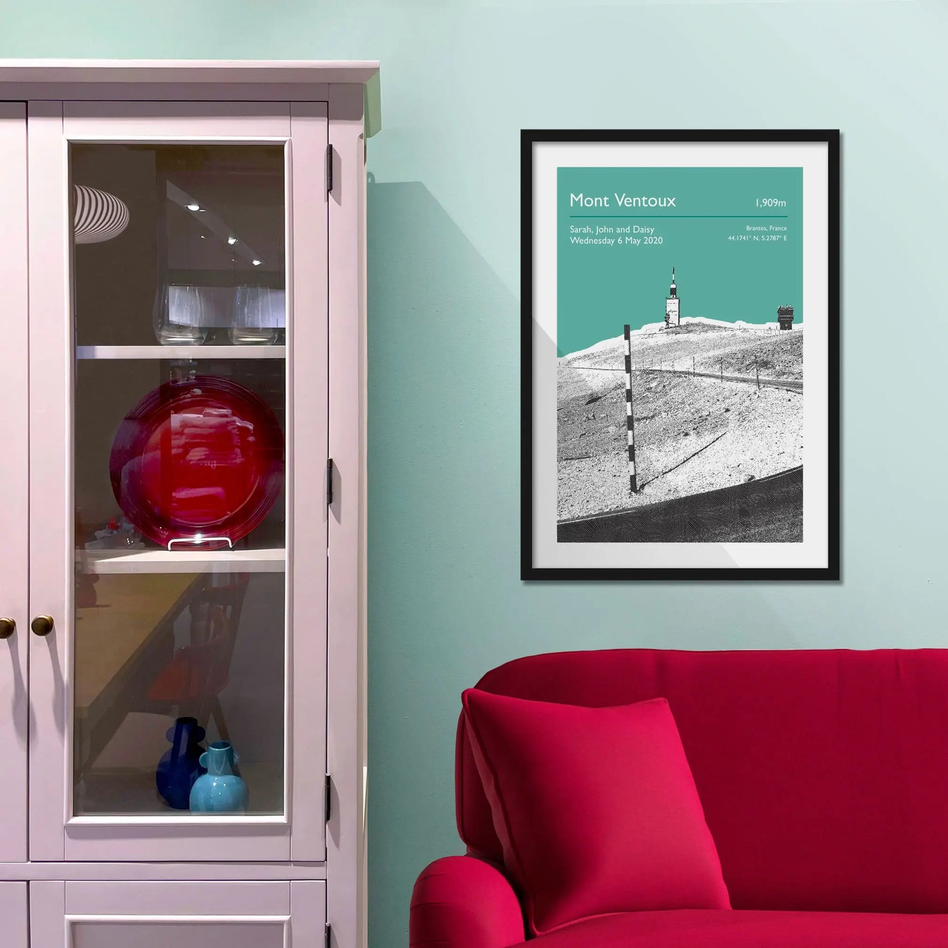 Framed picture on a baby blue wall beside pink shelving