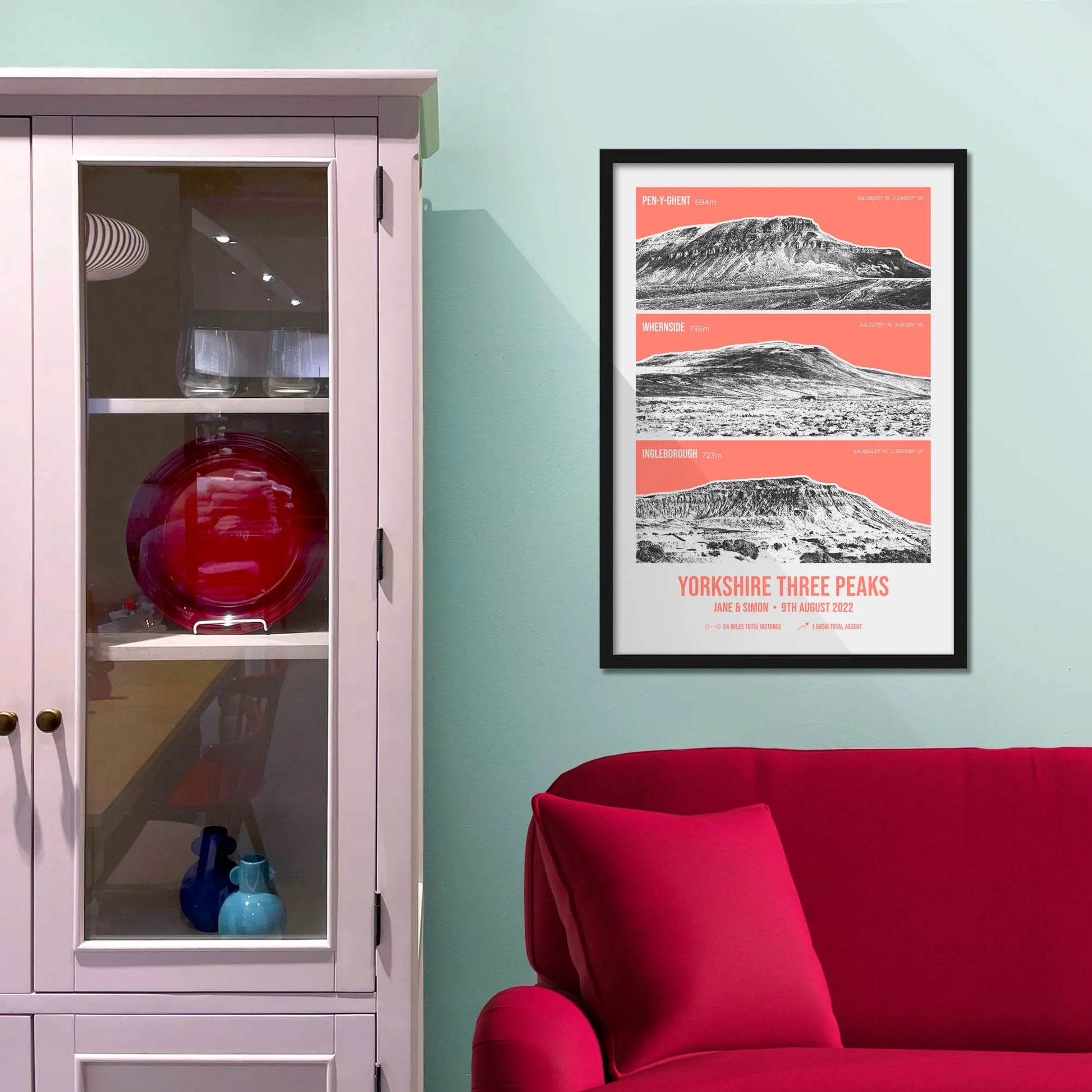 Framed print on baby blue wall beside pink shelves and behind a red sofa