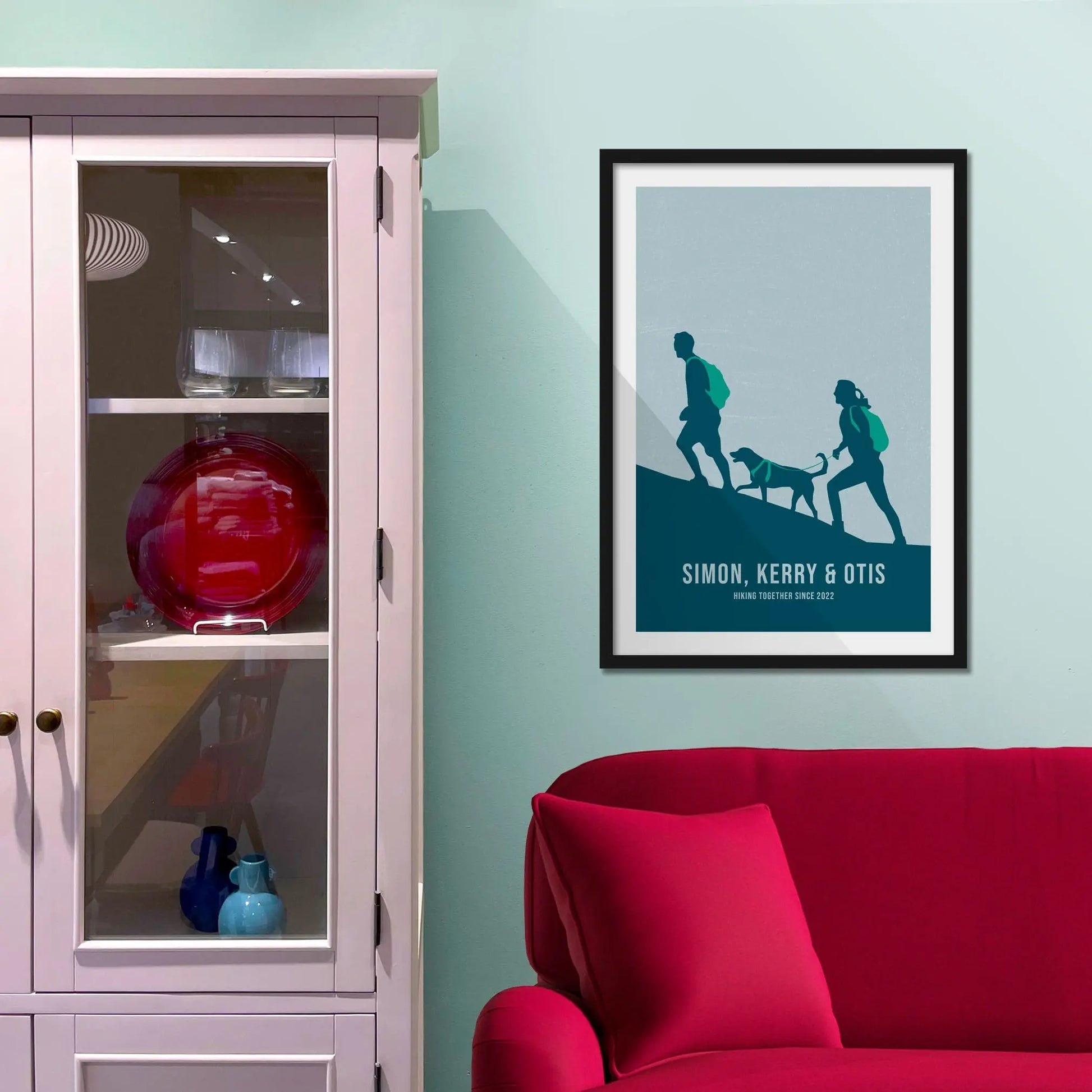 Framed print on light blue wall beside pink shelving unit.