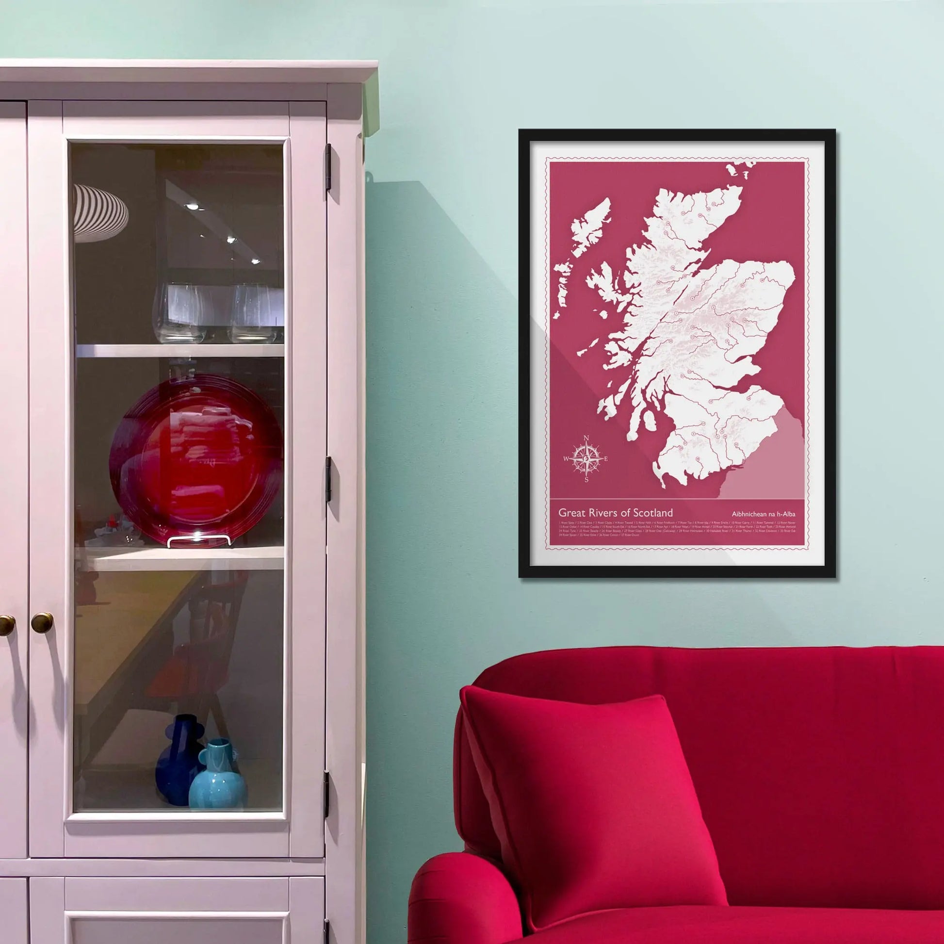 Framed picture on a baby blue wall beside pink shelving