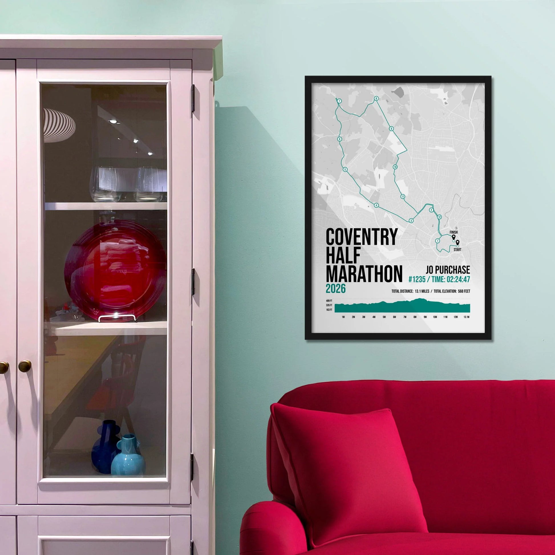 Framed picture on a baby blue wall beside pink shelving