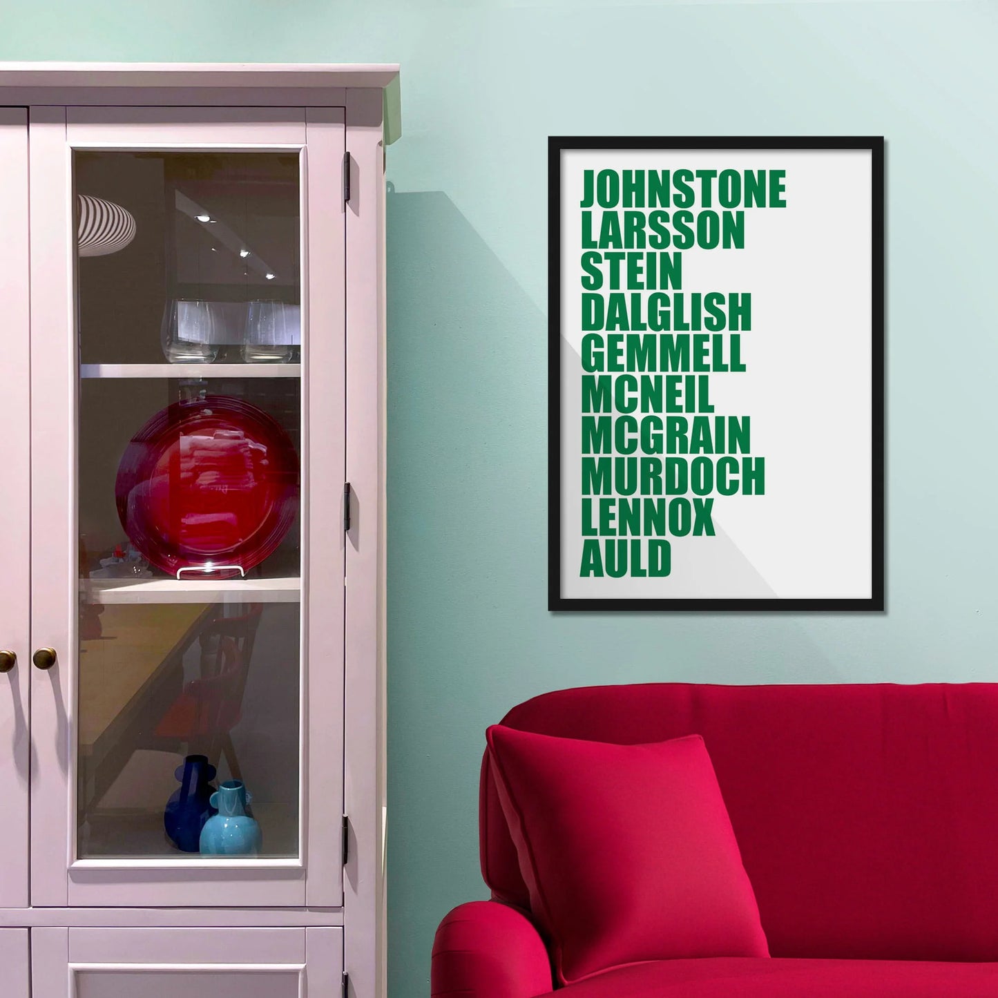 Framed picture on blue wall beside shelves above a red sofa