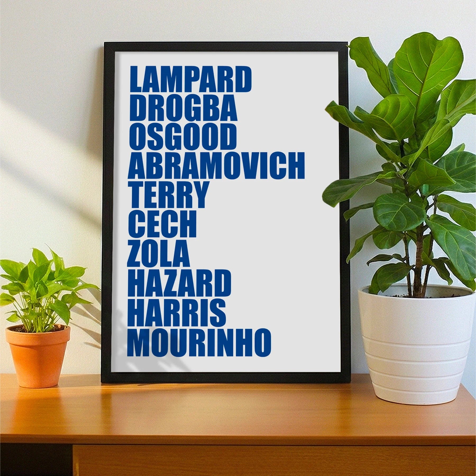 Framed print on sideboard beside a plant