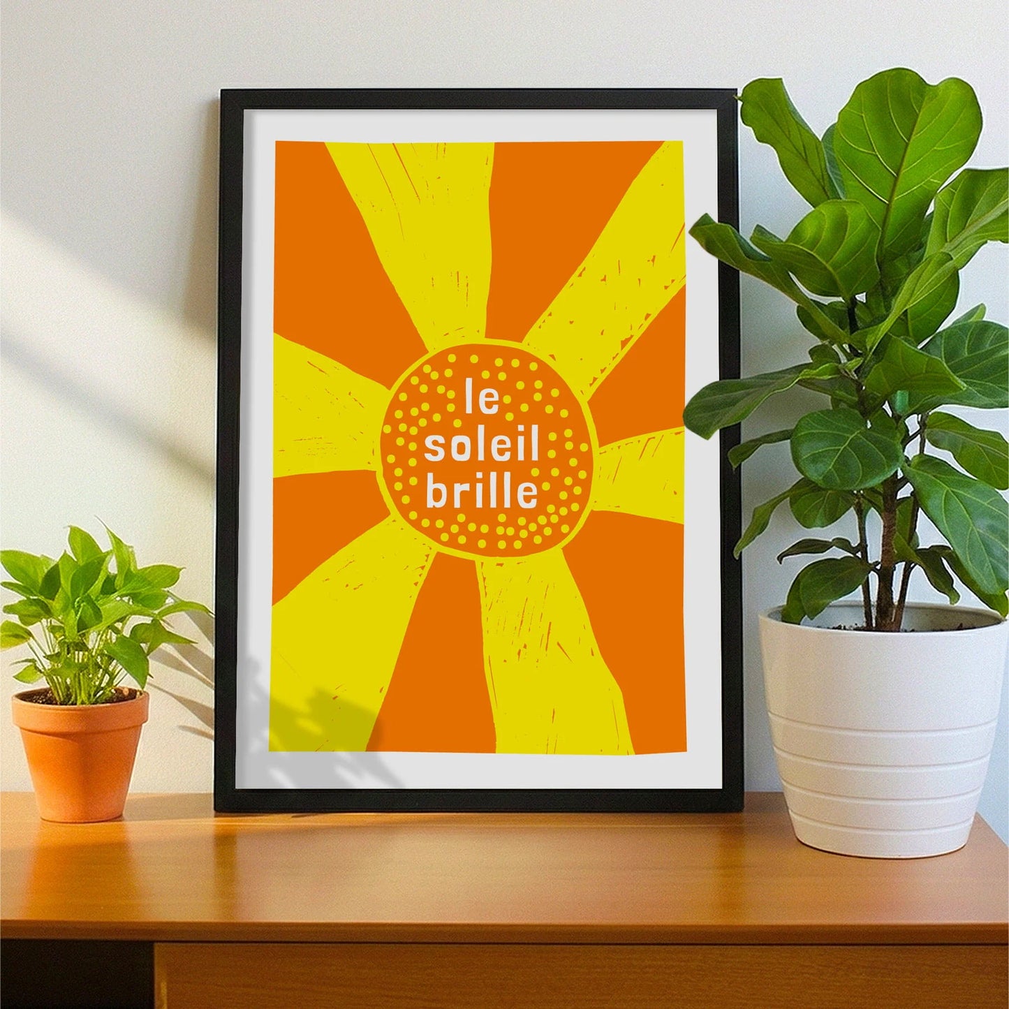 Framed print on sideboard beside a plant