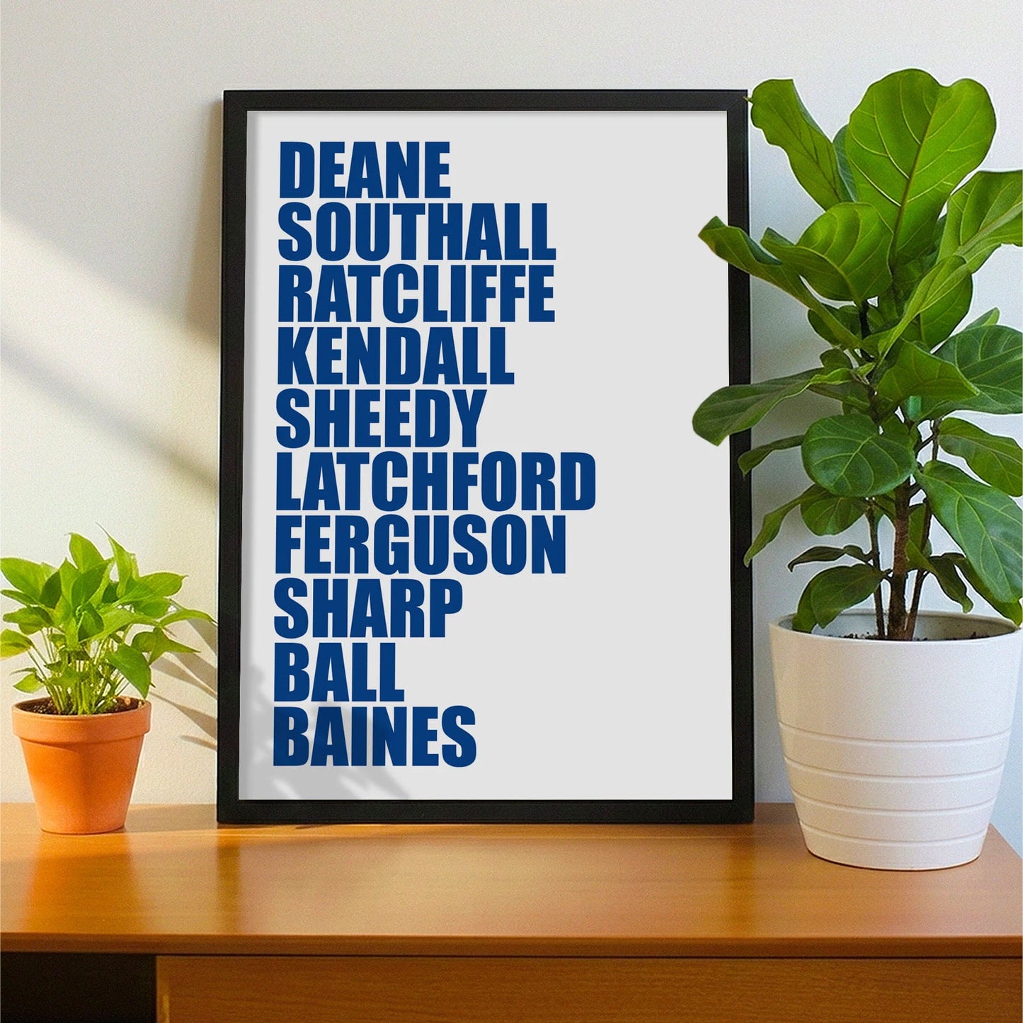 Framed print on sideboard beside a plant