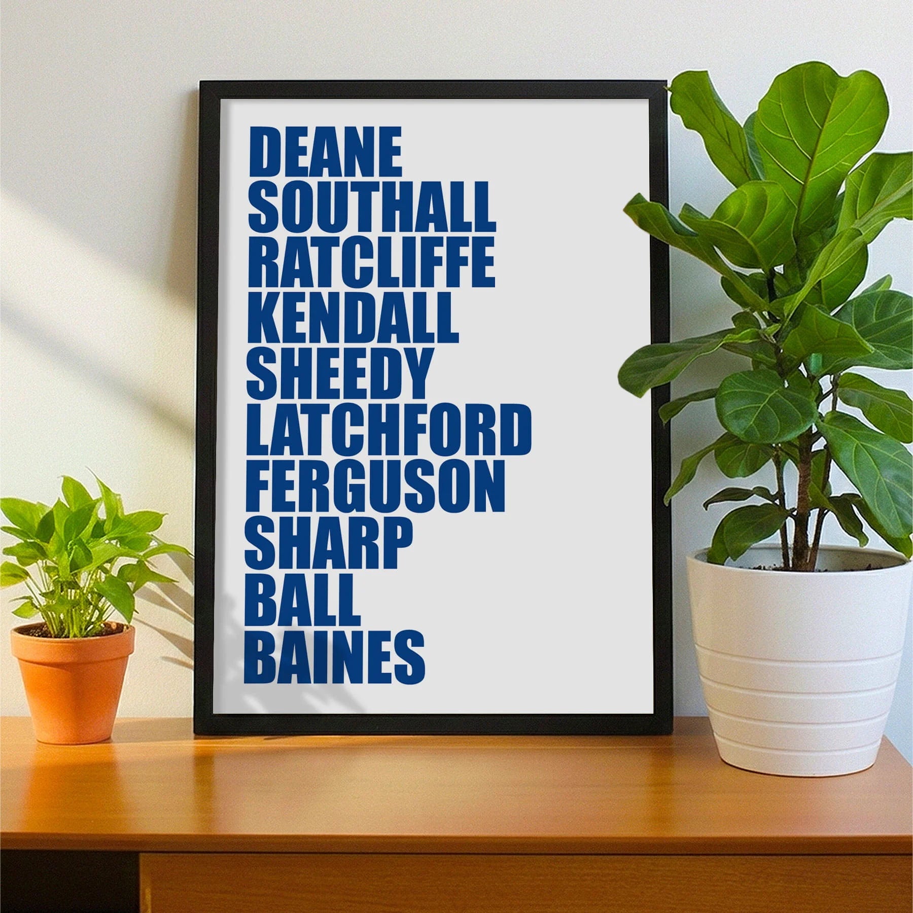 Framed print on sideboard beside a plant