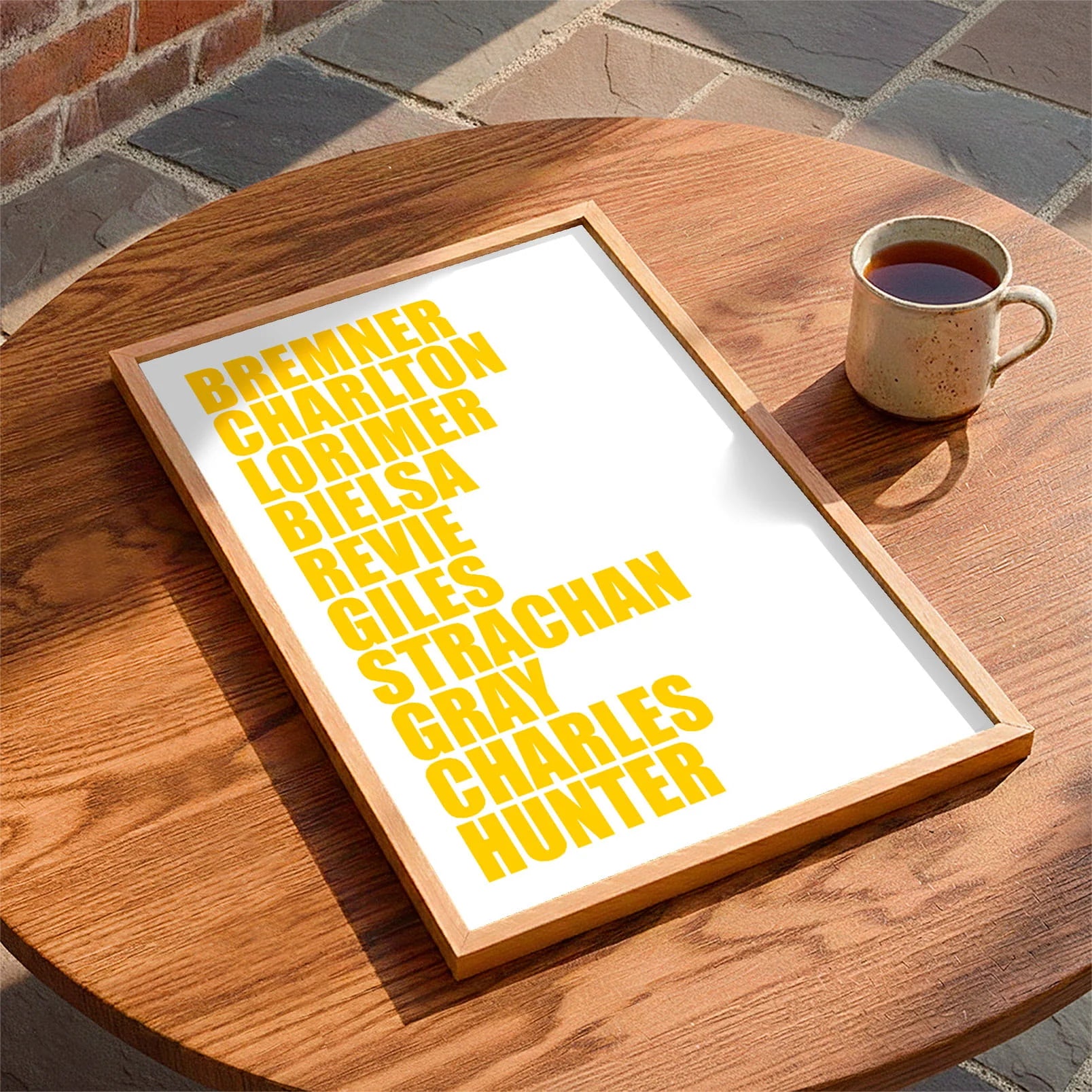 Framed print laying on a table beside a mug of tea