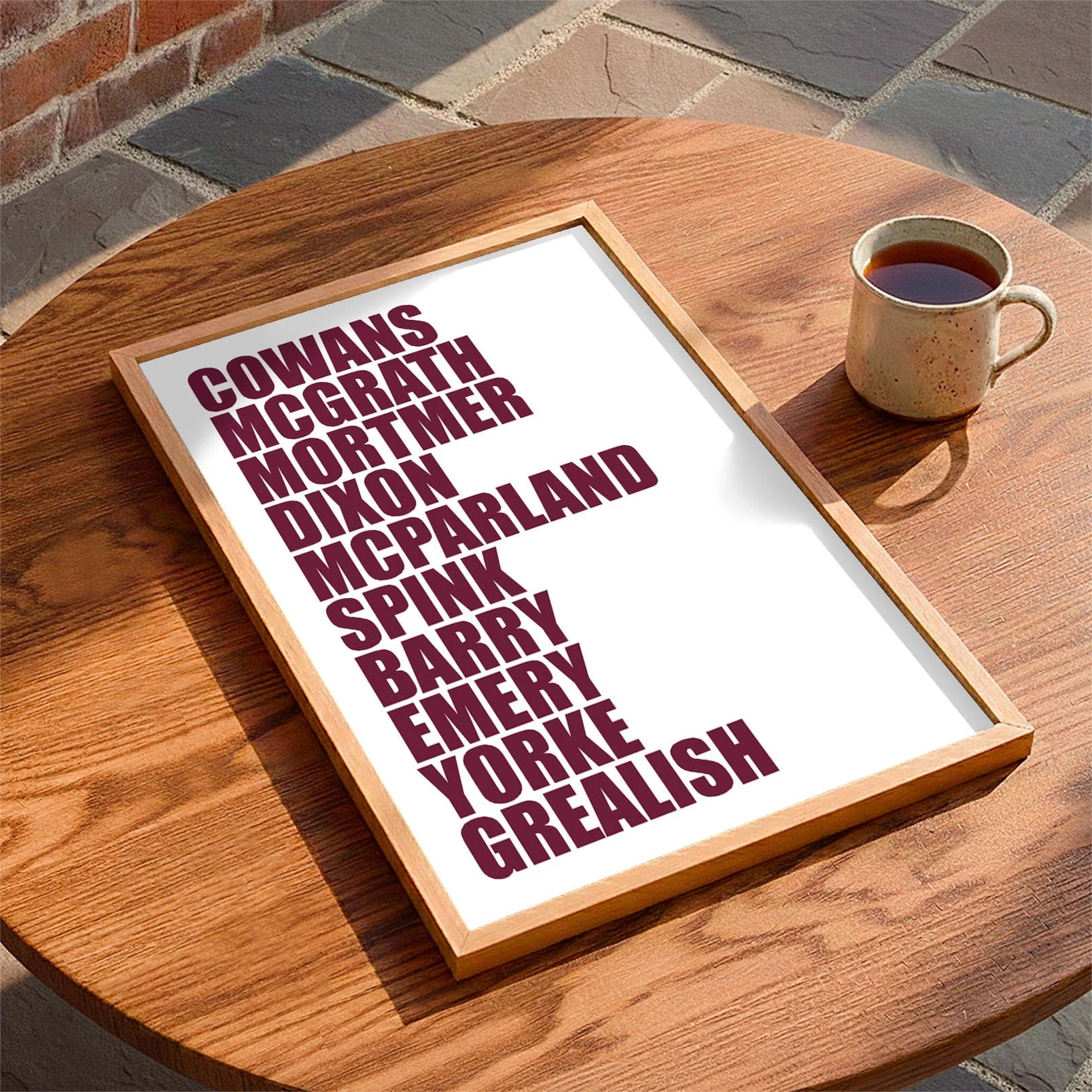 Framed print laying on a table beside a mug of tea