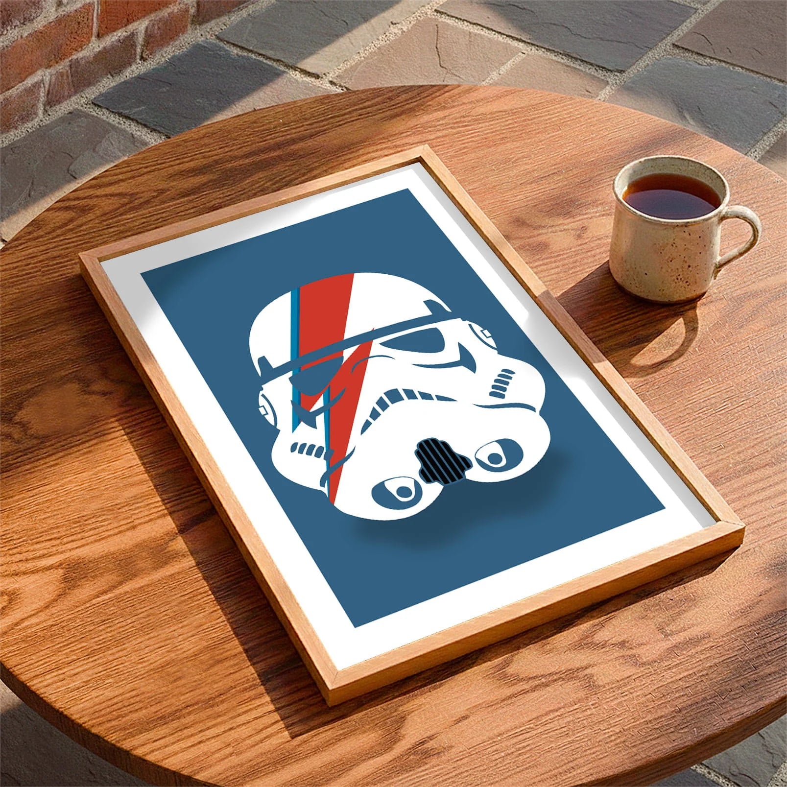 Framed print laying on a table beside a mug of tea