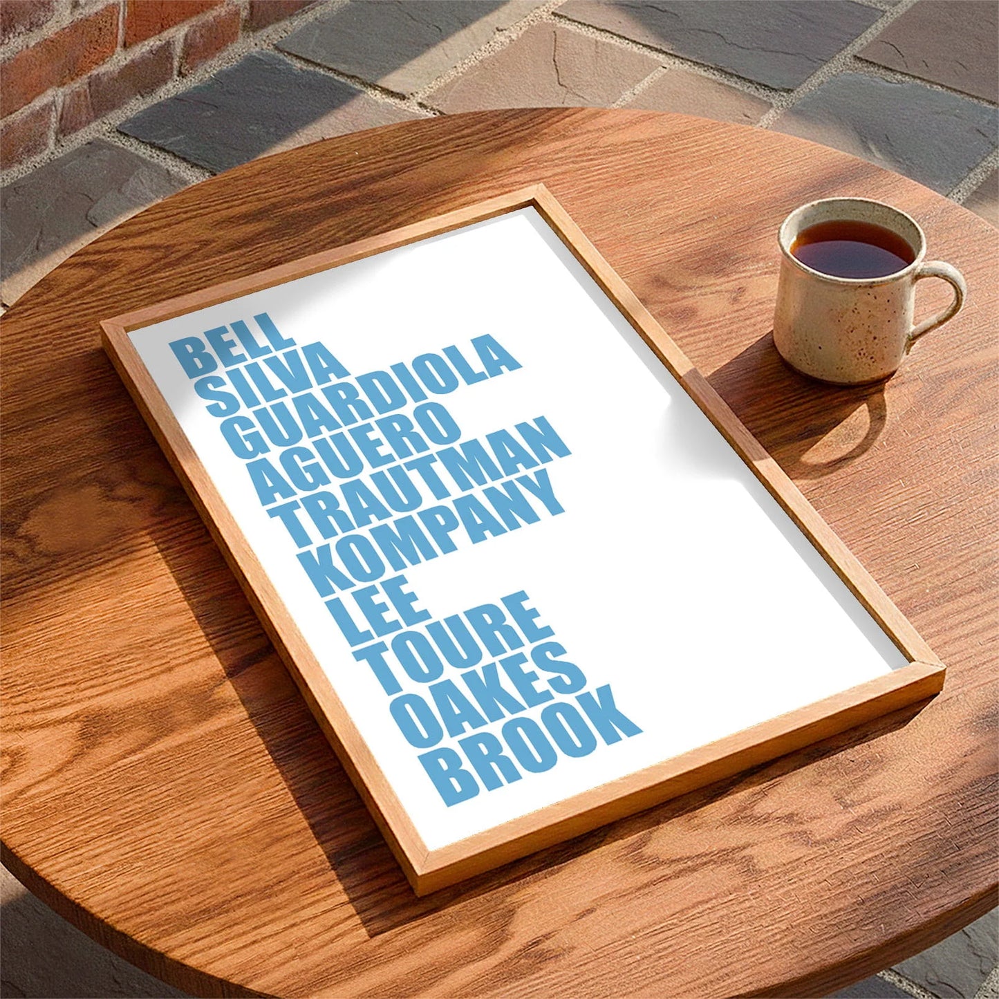 Framed print laying on a table beside a mug of tea