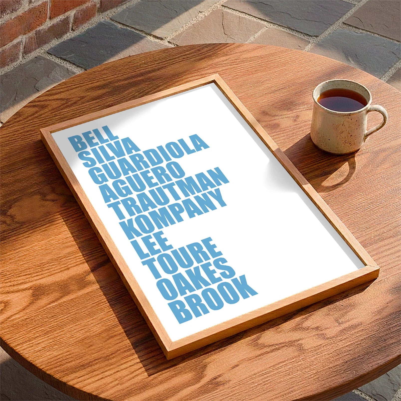 Framed print laying on a table beside a mug of tea