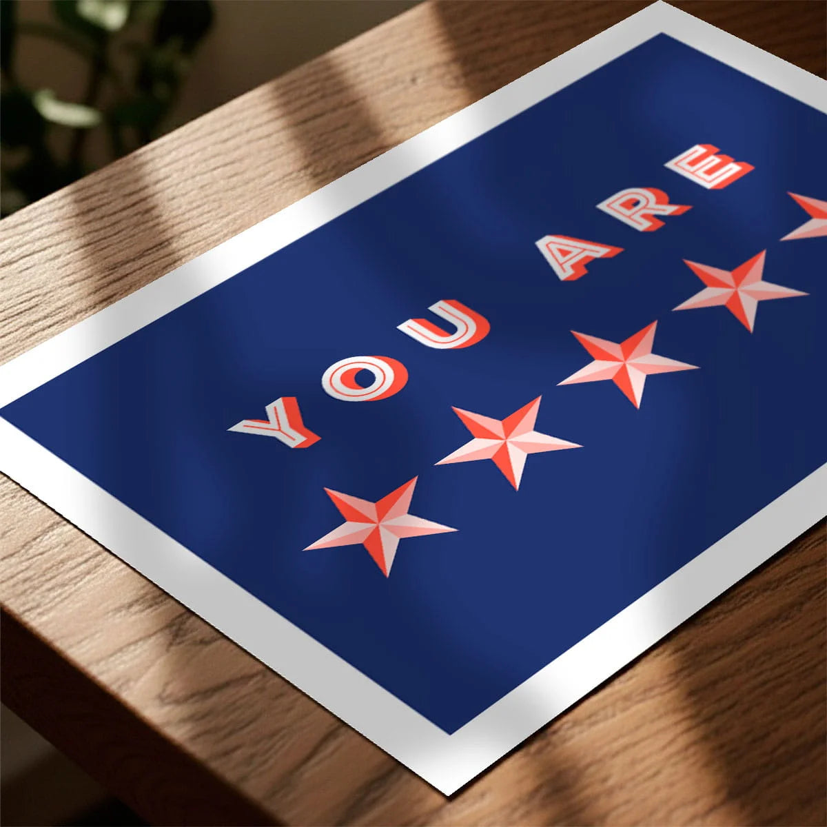 Print laying on table with speckled shade cast across the surface