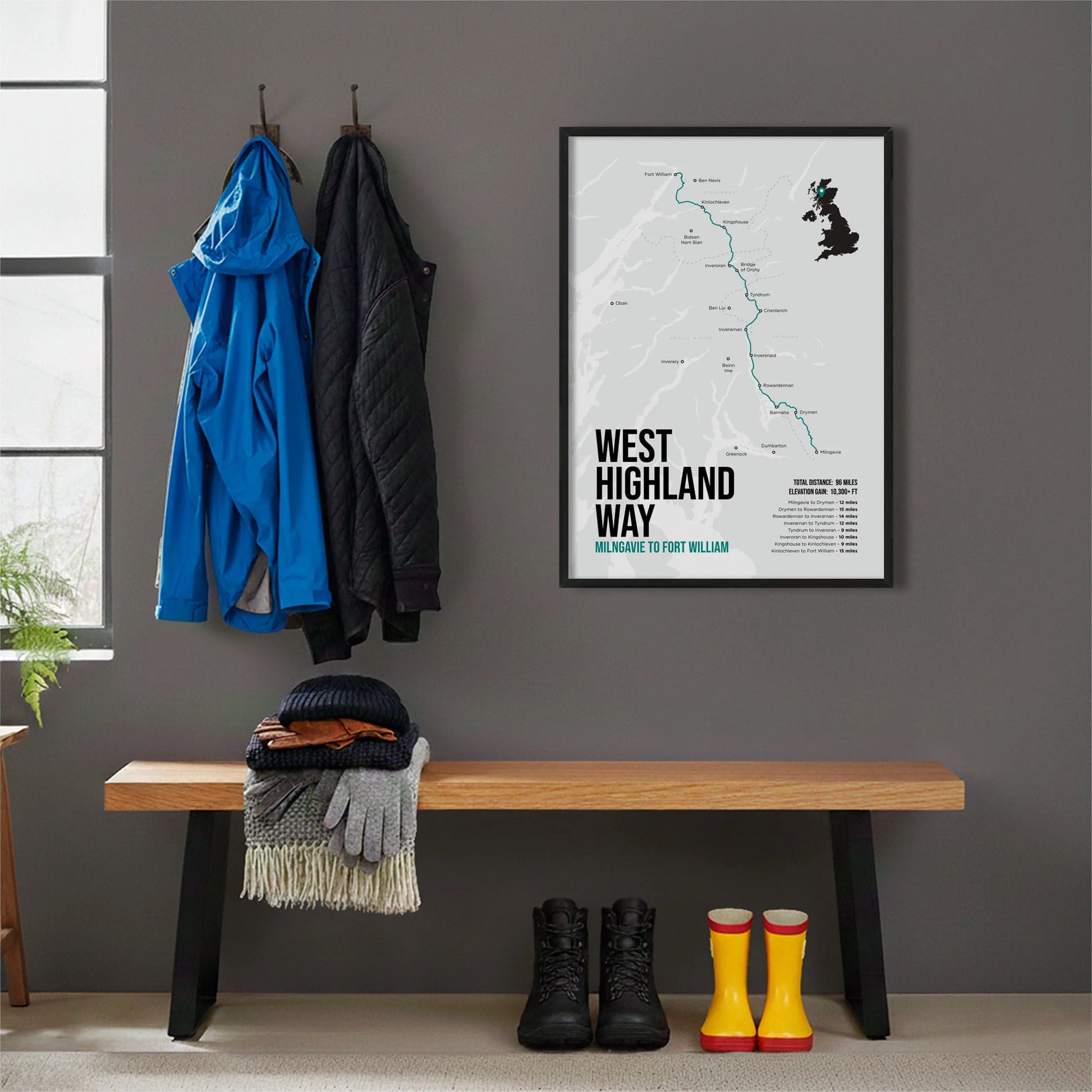 Framed print hanging on grey wall beside coats hanging above bench with walking boots and a scarf