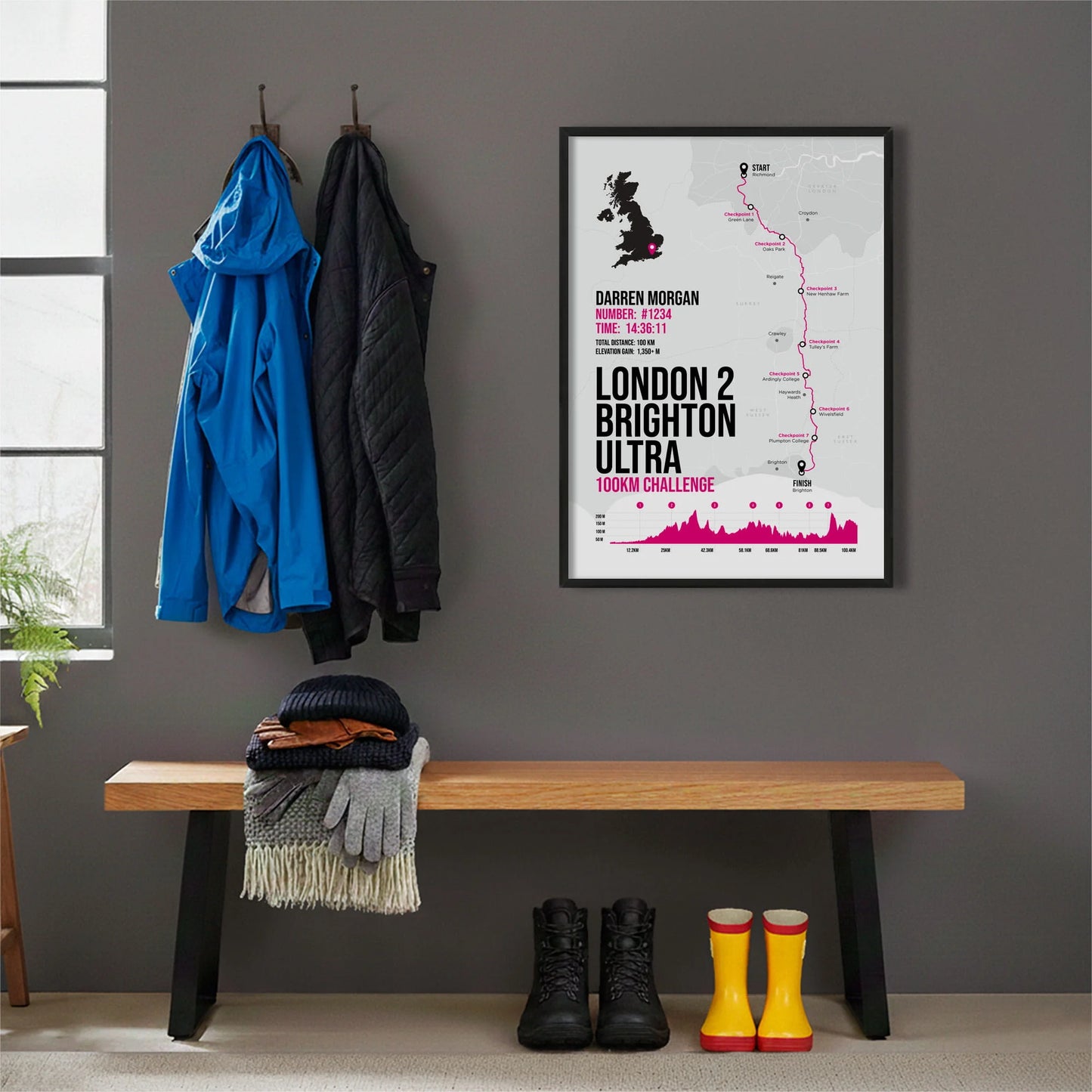 Framed print hanging on grey wall beside coats on hooks above walking boots and shows
