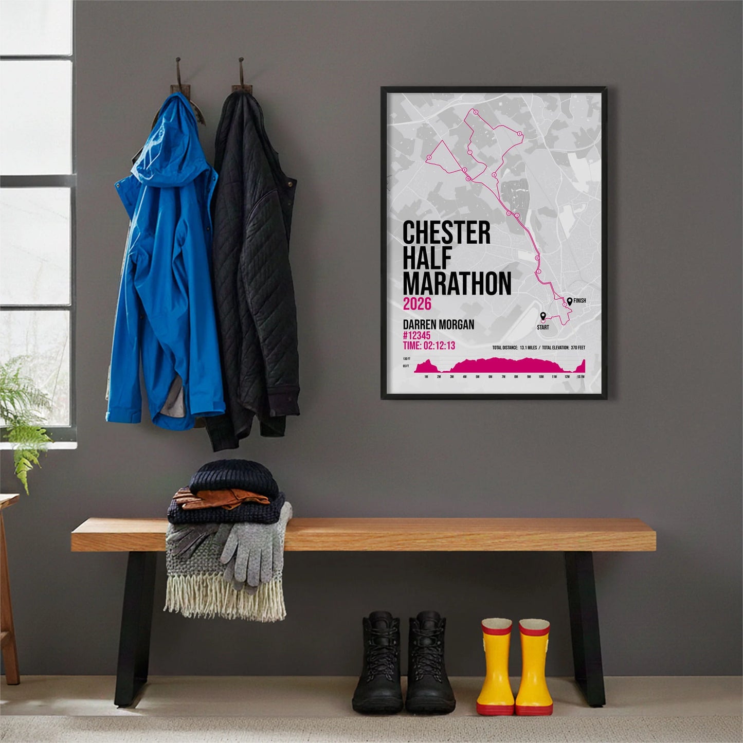 Framed print hanging on grey wall beside coats on hooks above walking boots and shows