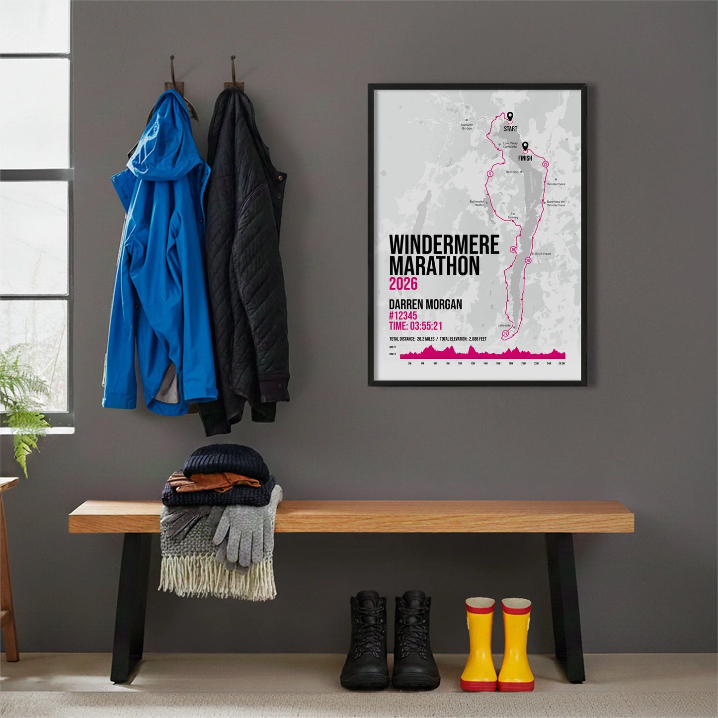 Framed print hanging on grey wall beside coats on hooks above walking boots and shows