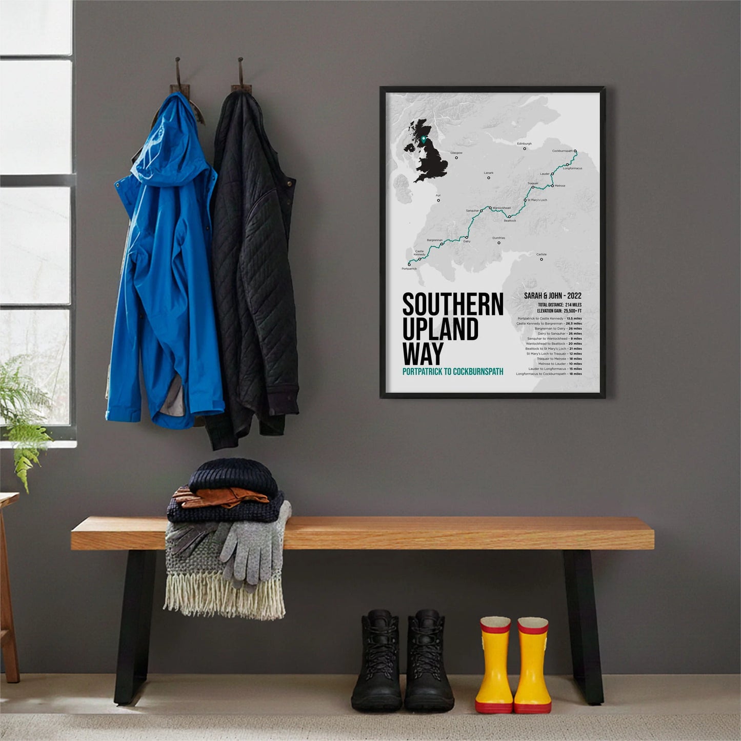 Framed print hanging on grey wall beside coats hanging above bench with walking boots and a scarf