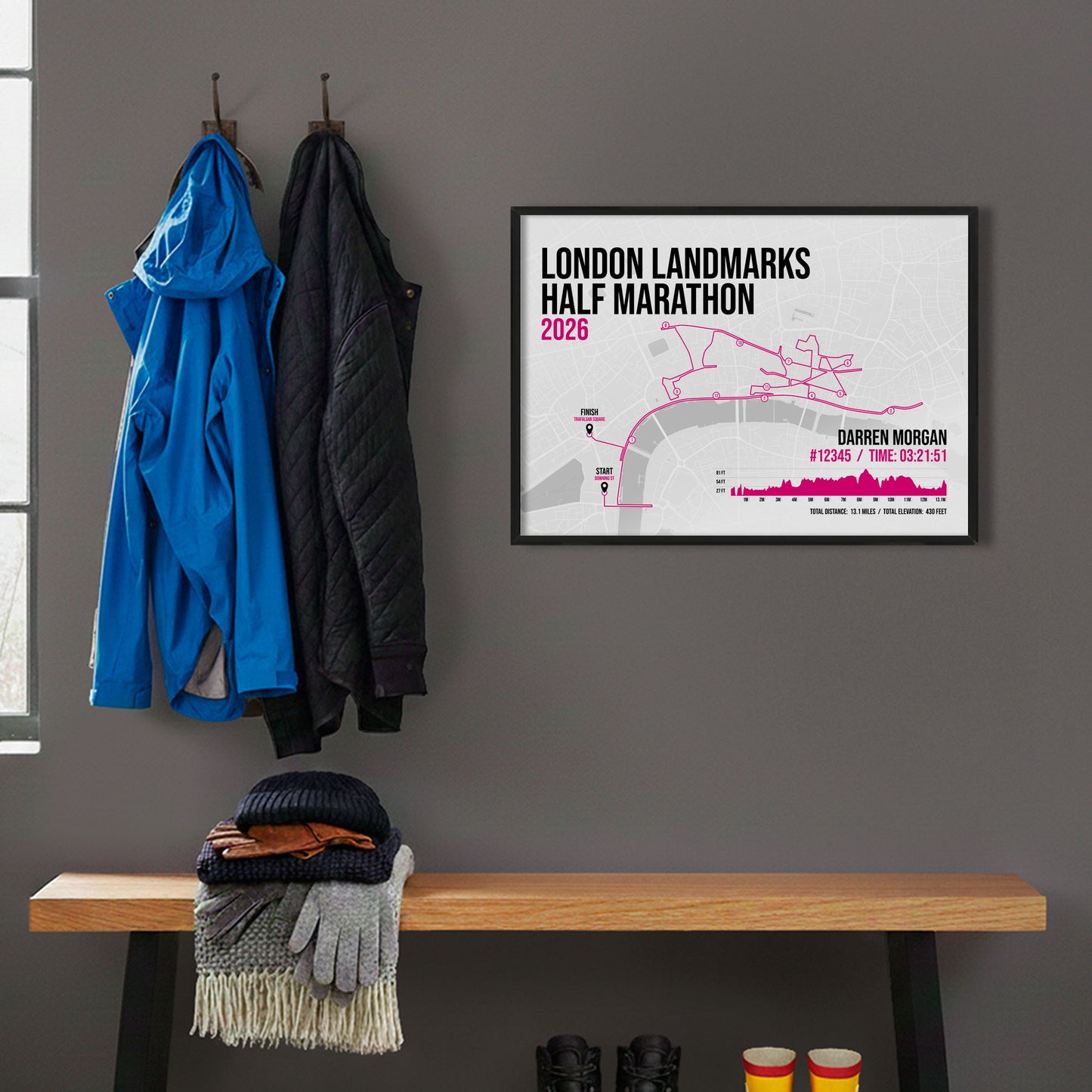 Framed print hanging on grey wall beside coats hanging above bench with walking boots and a scarf