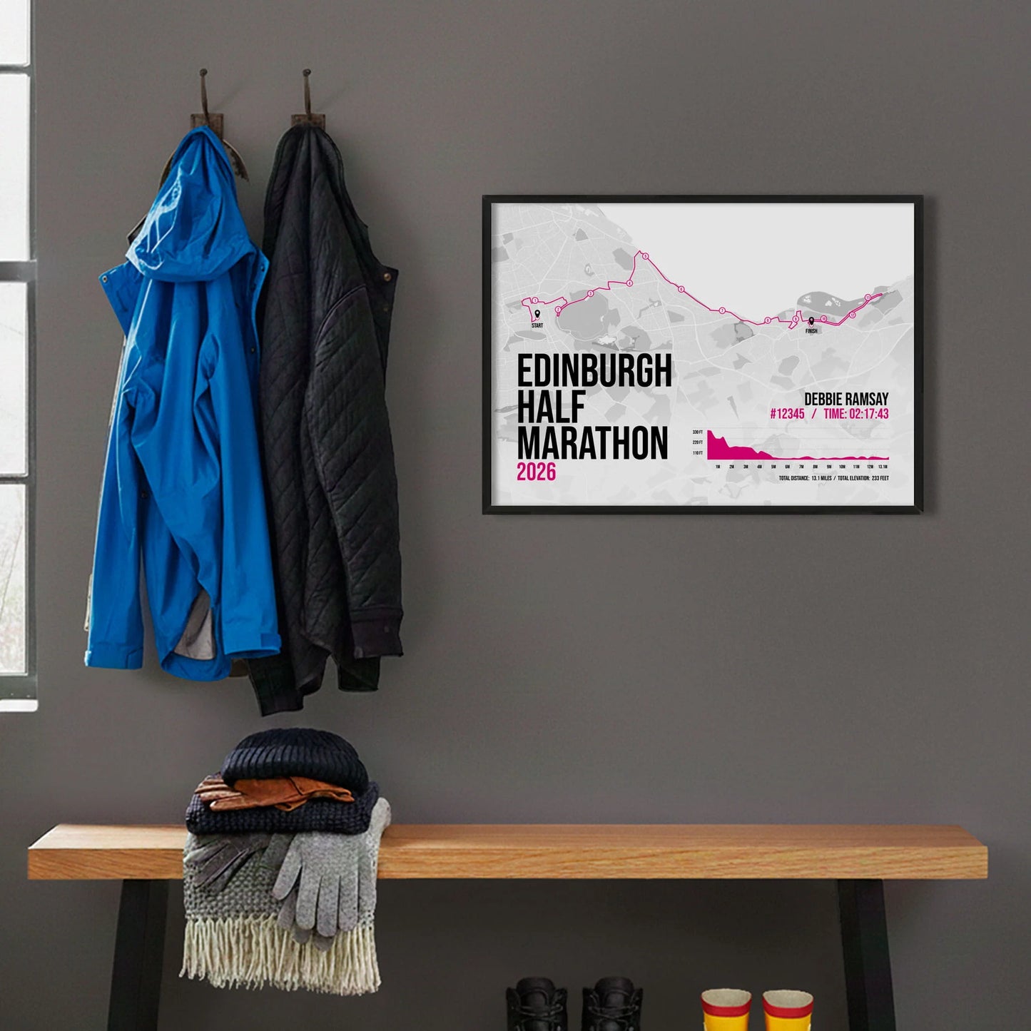 Framed print hanging on grey wall beside coats on hooks above walking boots and shows