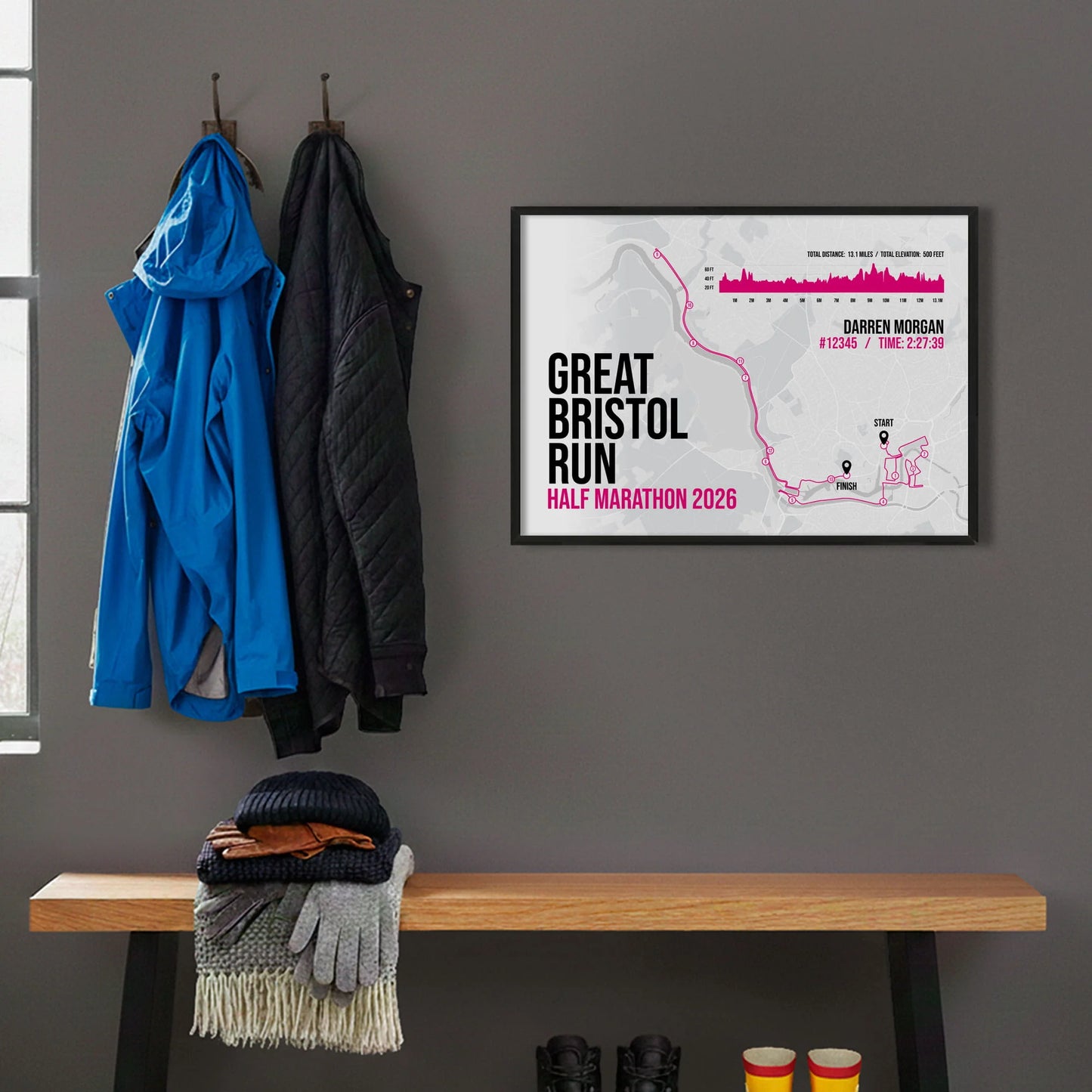 Framed print hanging on grey wall beside coats on hooks above walking boots and shows