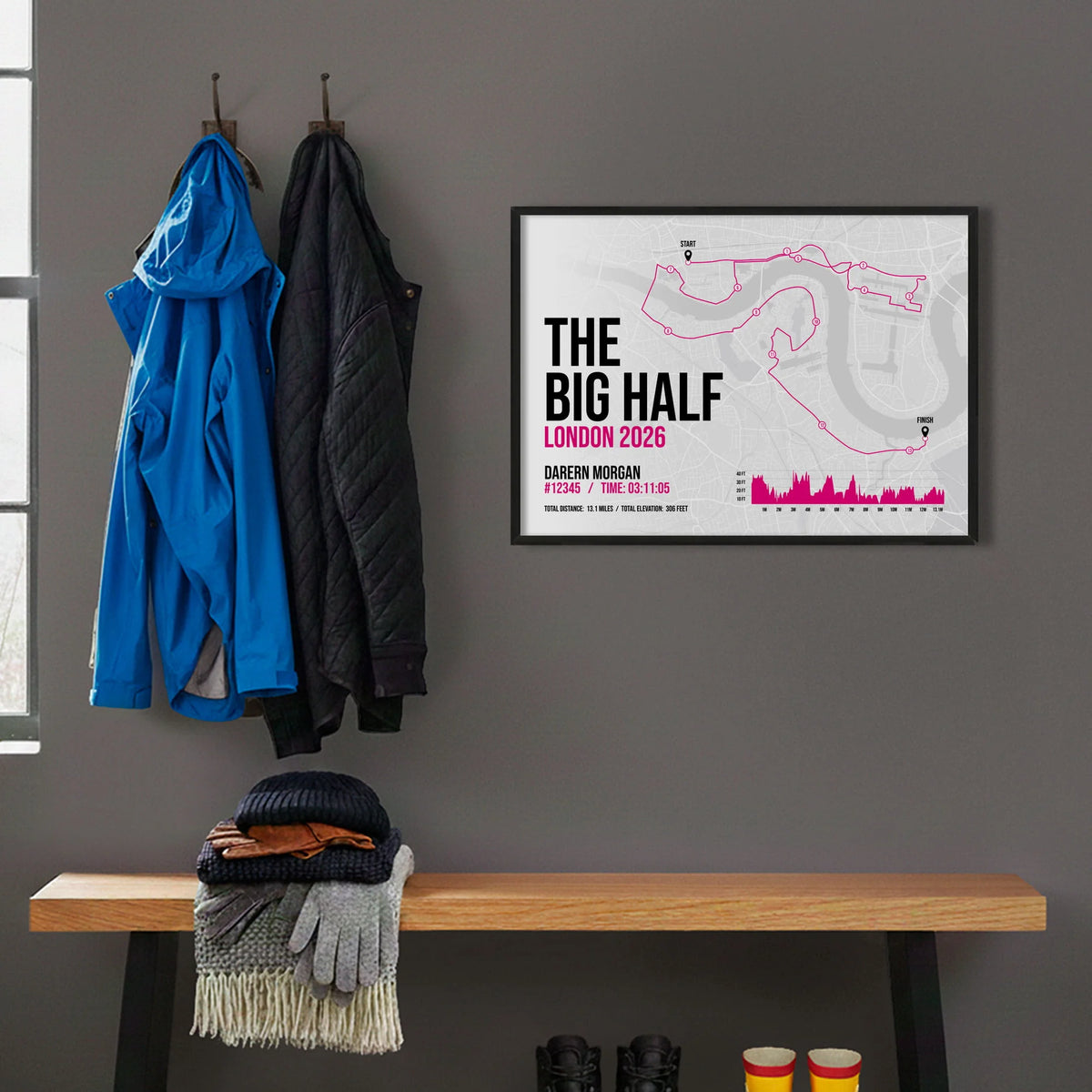 Framed print hanging on grey wall beside coats hanging above bench with walking boots and a scarf