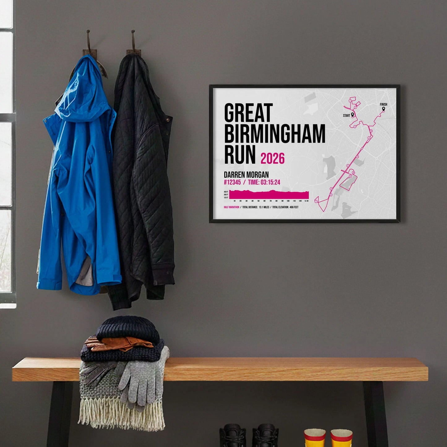 Framed print hanging on grey wall beside coats on hooks above walking boots and shows