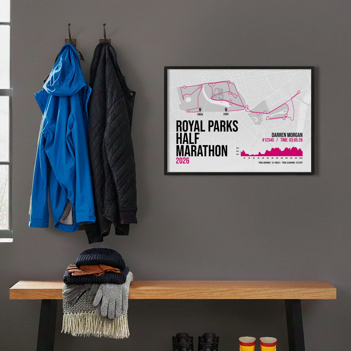 Framed print hanging on grey wall beside coats hanging above bench with walking boots and a scarf