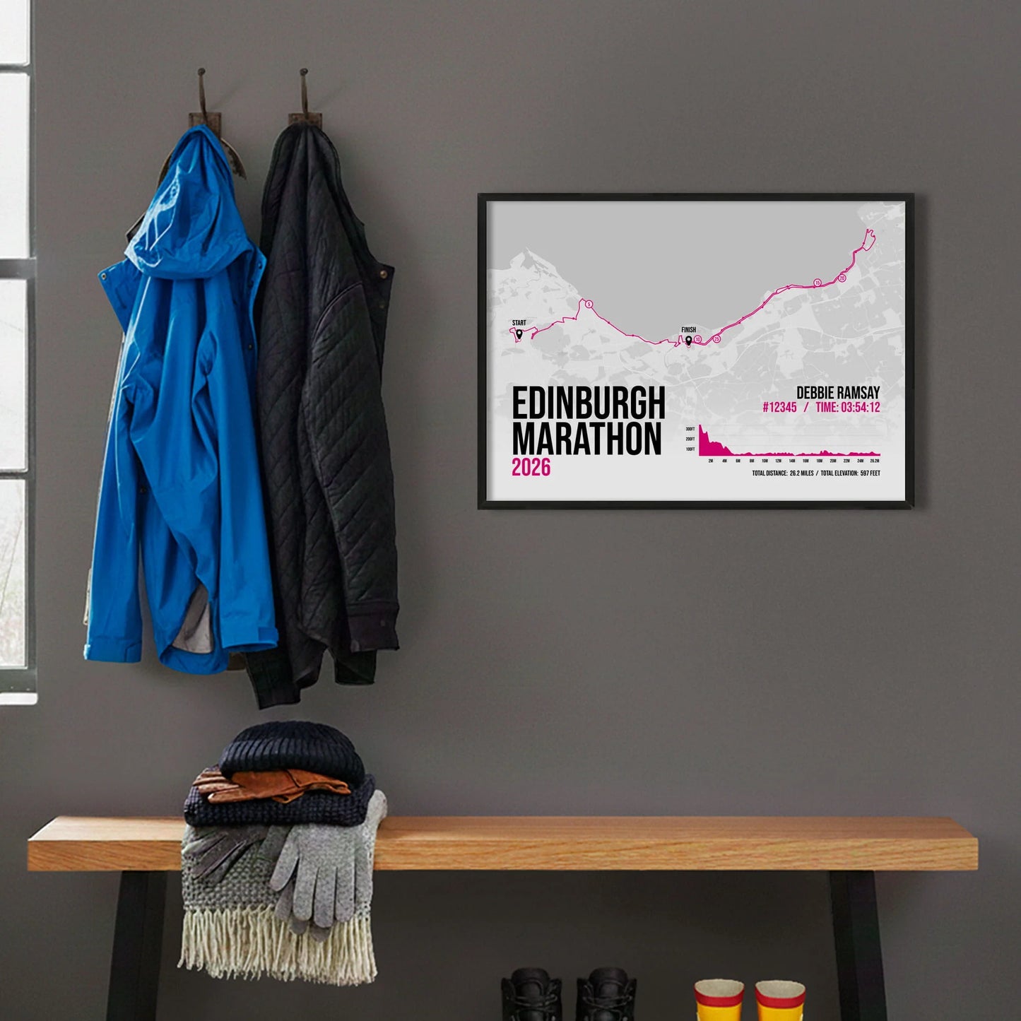 Framed print hanging on grey wall beside coats on hooks above walking boots and shows