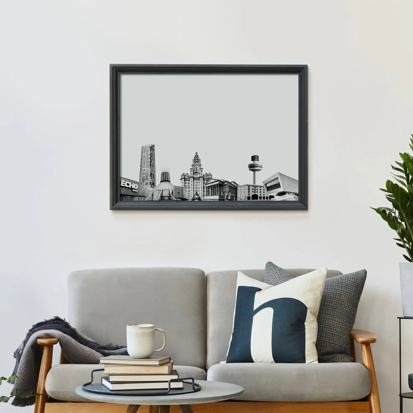 Framed print on wall above a sofa covered in cushions with a coffee table in front.