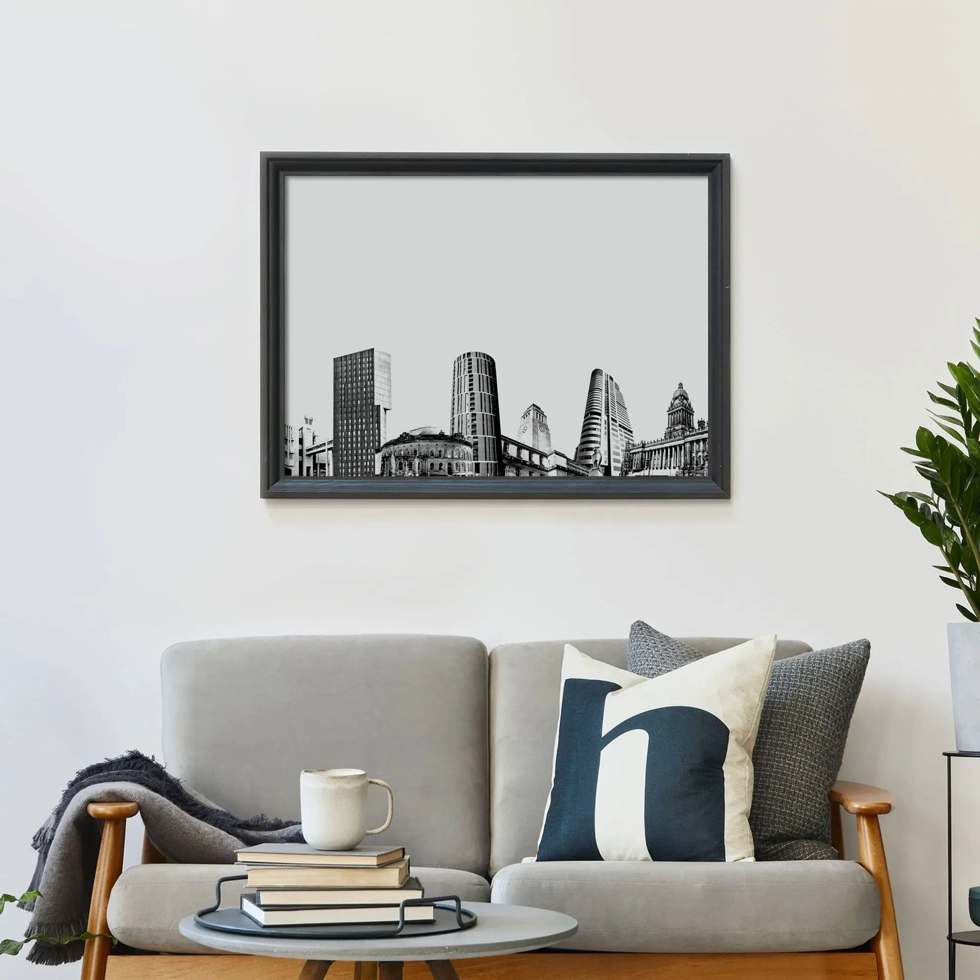 Framed print on wall above a sofa covered in cushions with a coffee table in front.