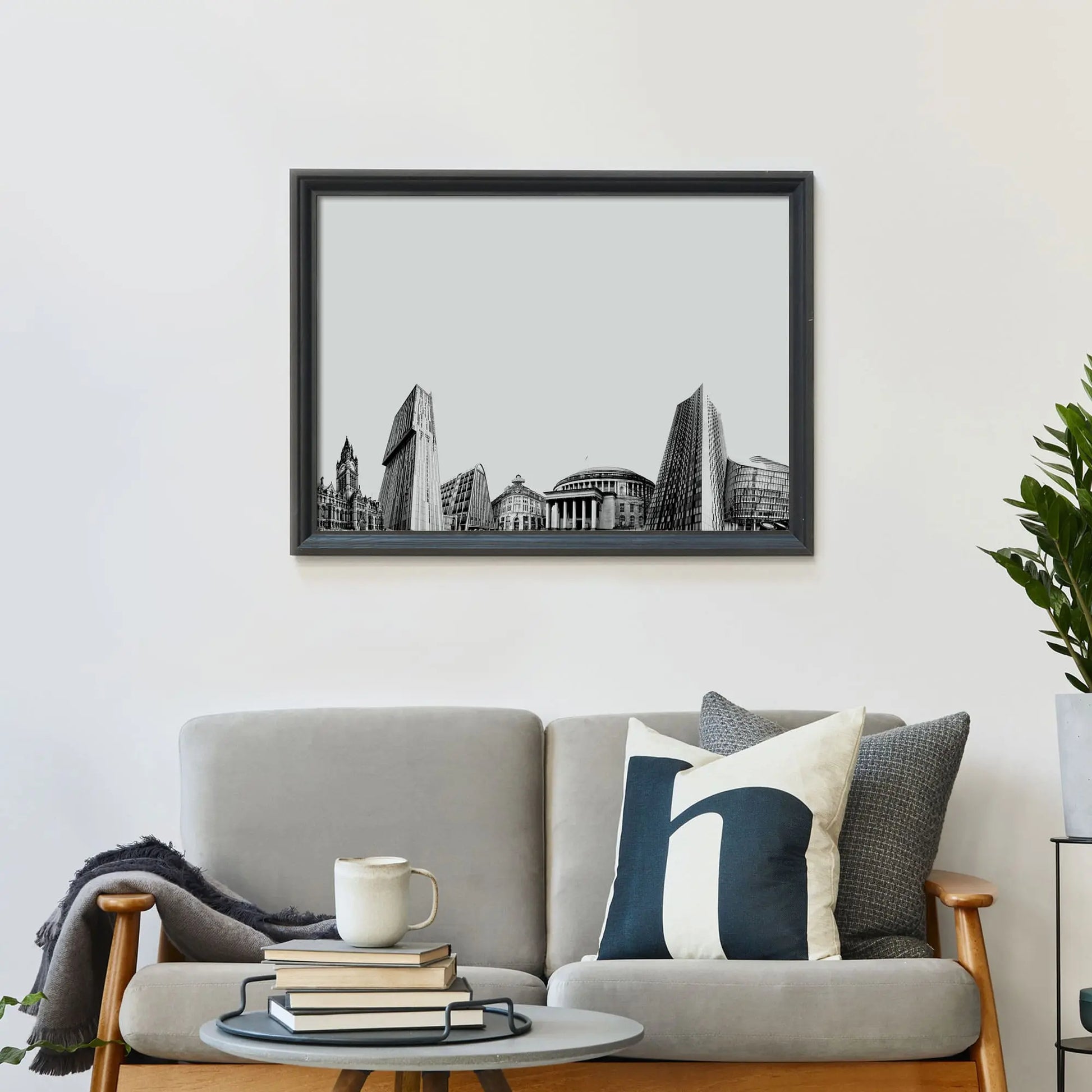 Framed print on wall above a sofa covered in cushions with a coffee table in front.