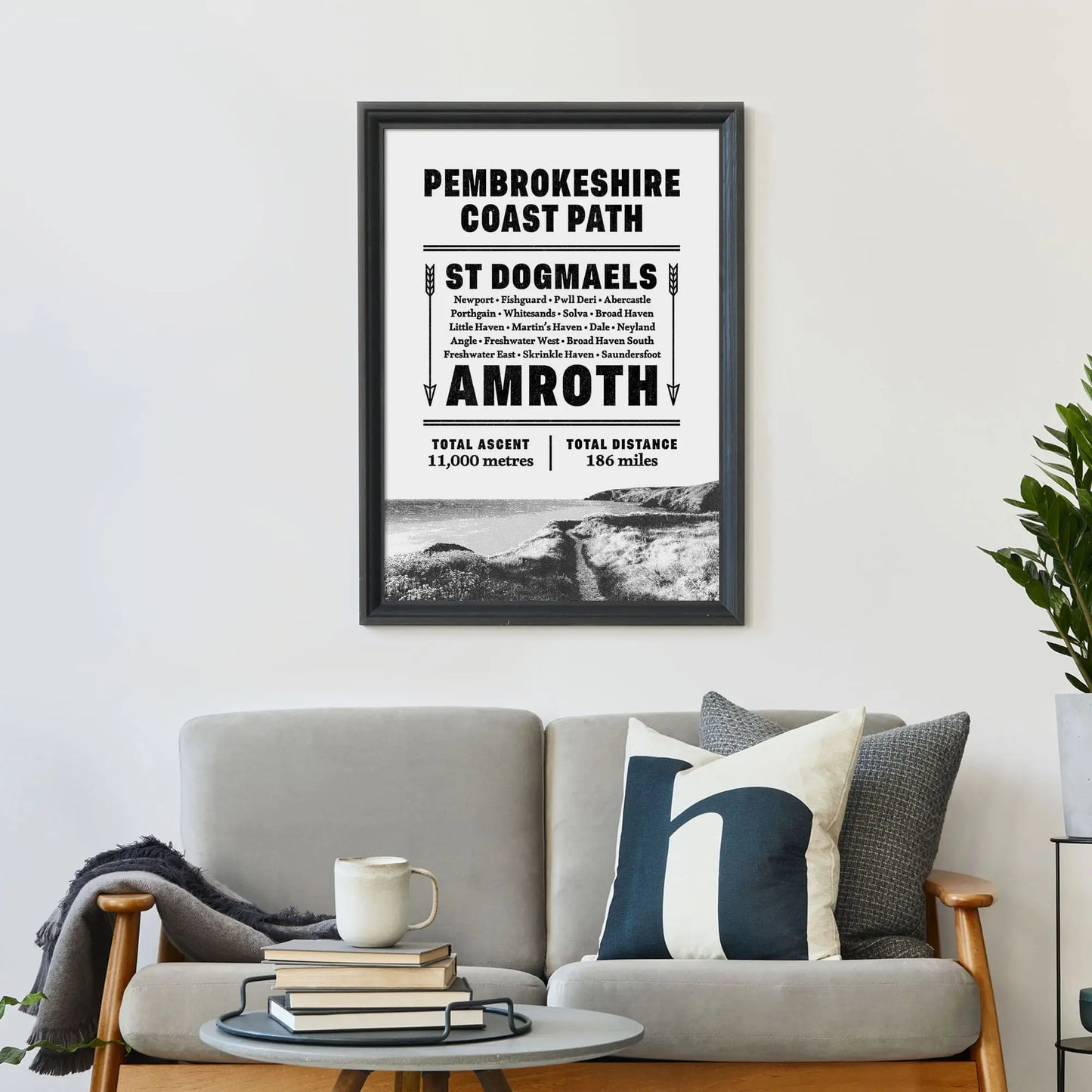 Framed print on wall above a sofa covered in cushions with a coffee table in front.