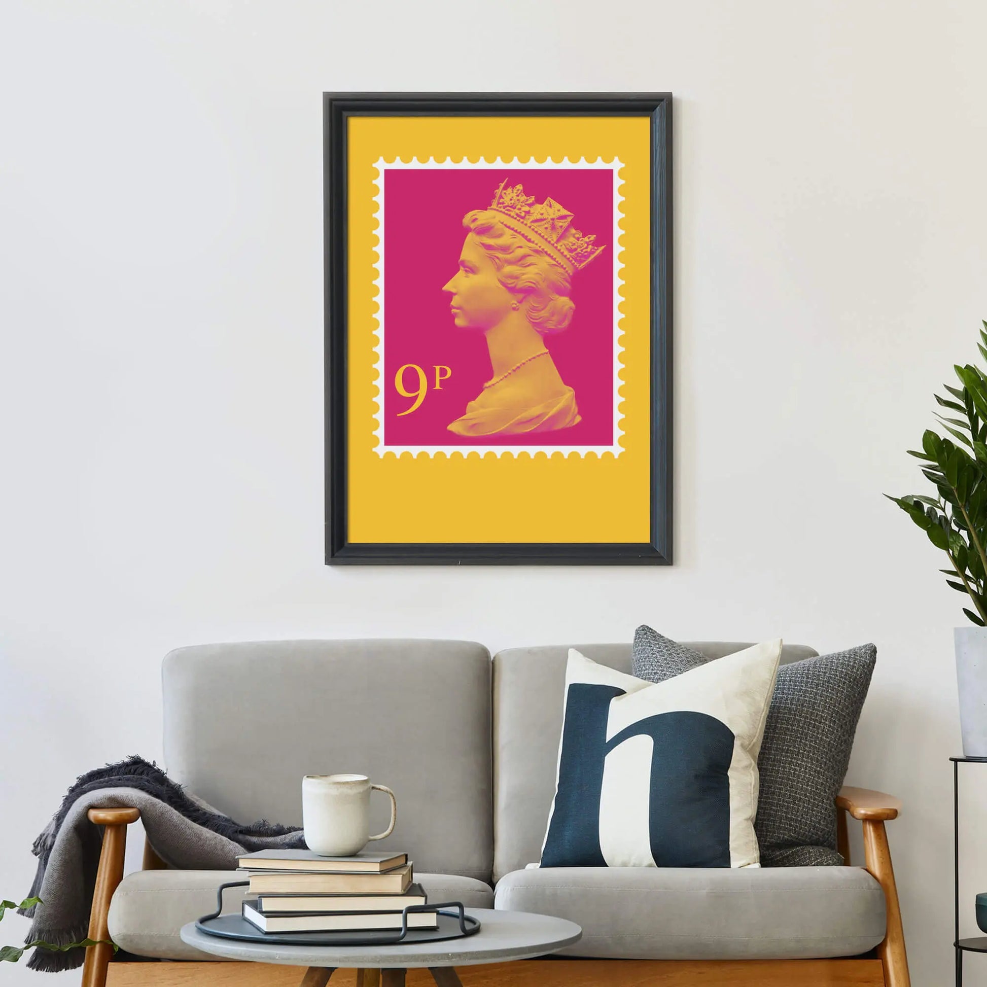 Framed print on wall above a sofa covered in cushions with a coffee table in front.