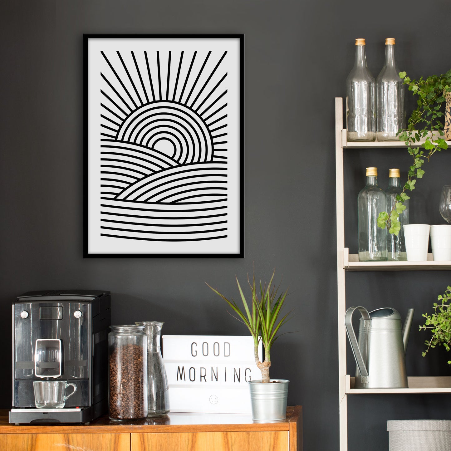 Kitchen wall infront of which is a sideboard with a coffee machine and a set of shelves holding bottles and plants. On the wall above the sideboard is the framed print in a black frame on a dark grey wall.