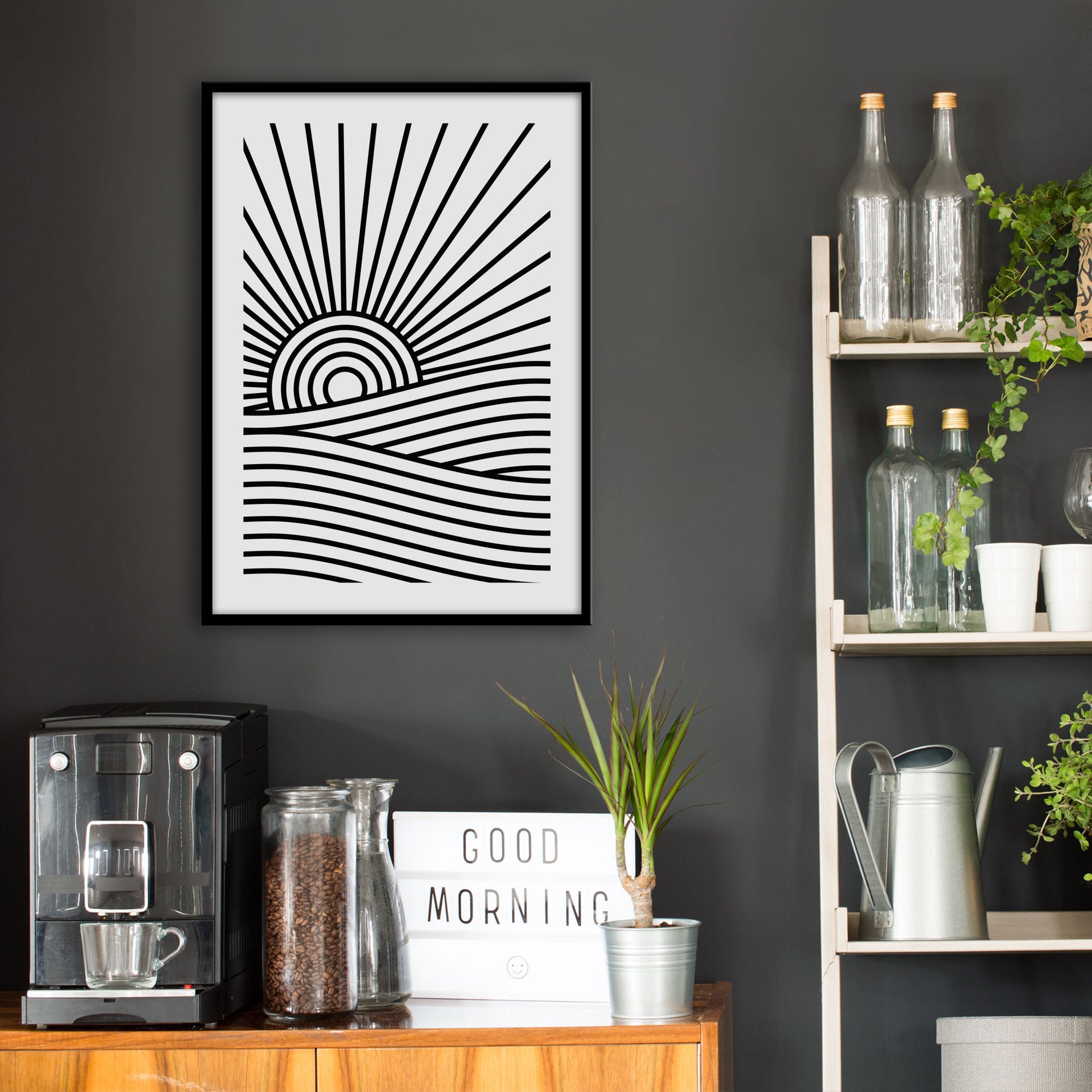 Kitchen wall infront of which is a sideboard with a coffee machine and a set of shelves holding bottles and plants. On the wall above the sideboard is the framed print in a black frame on a dark grey wall.